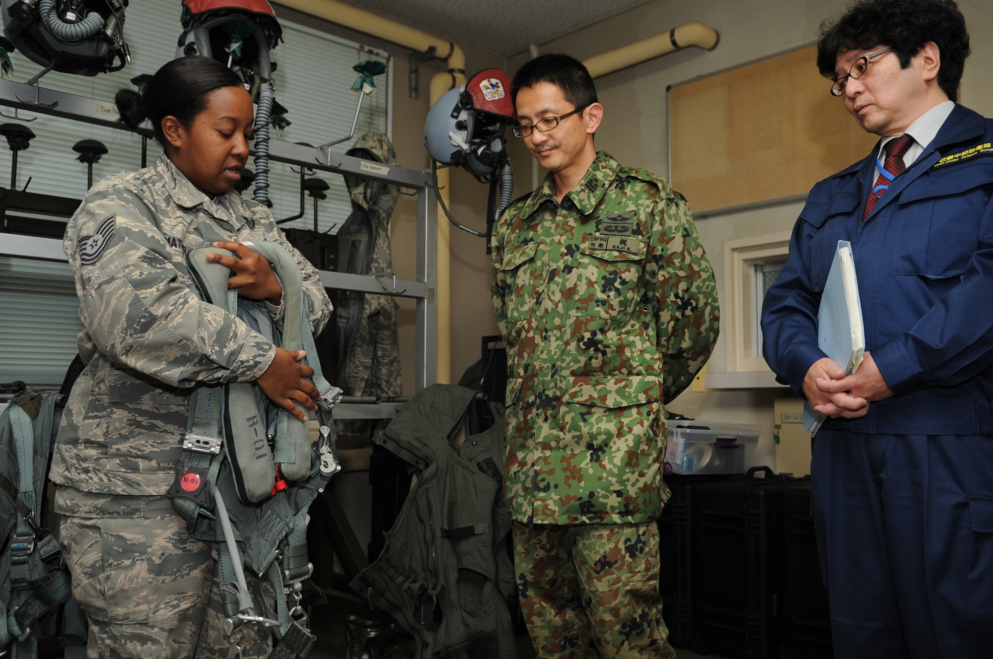 U.S. Air Force Tech. Sgt. Nicole Mather, 18th Operations Support Squadron aircrew flight equipment craftsman, shows Japanese Ground Self Defense Force Col. Koichiro Kaji, defense advisor, and Shinji Yamamoto, a member of the Japanese Ministry of Defense, a safety harness used by fighter pilots during a life support demonstration on Komatsu Air Base, Japan, Dec. 10, 2013. The demonstration was part of a week-long Aviation Training Relocation Program, which focused on interoperability and operational readiness. (U.S. Air Force photo by Staff Sgt. Amber E. N. Jacobs)