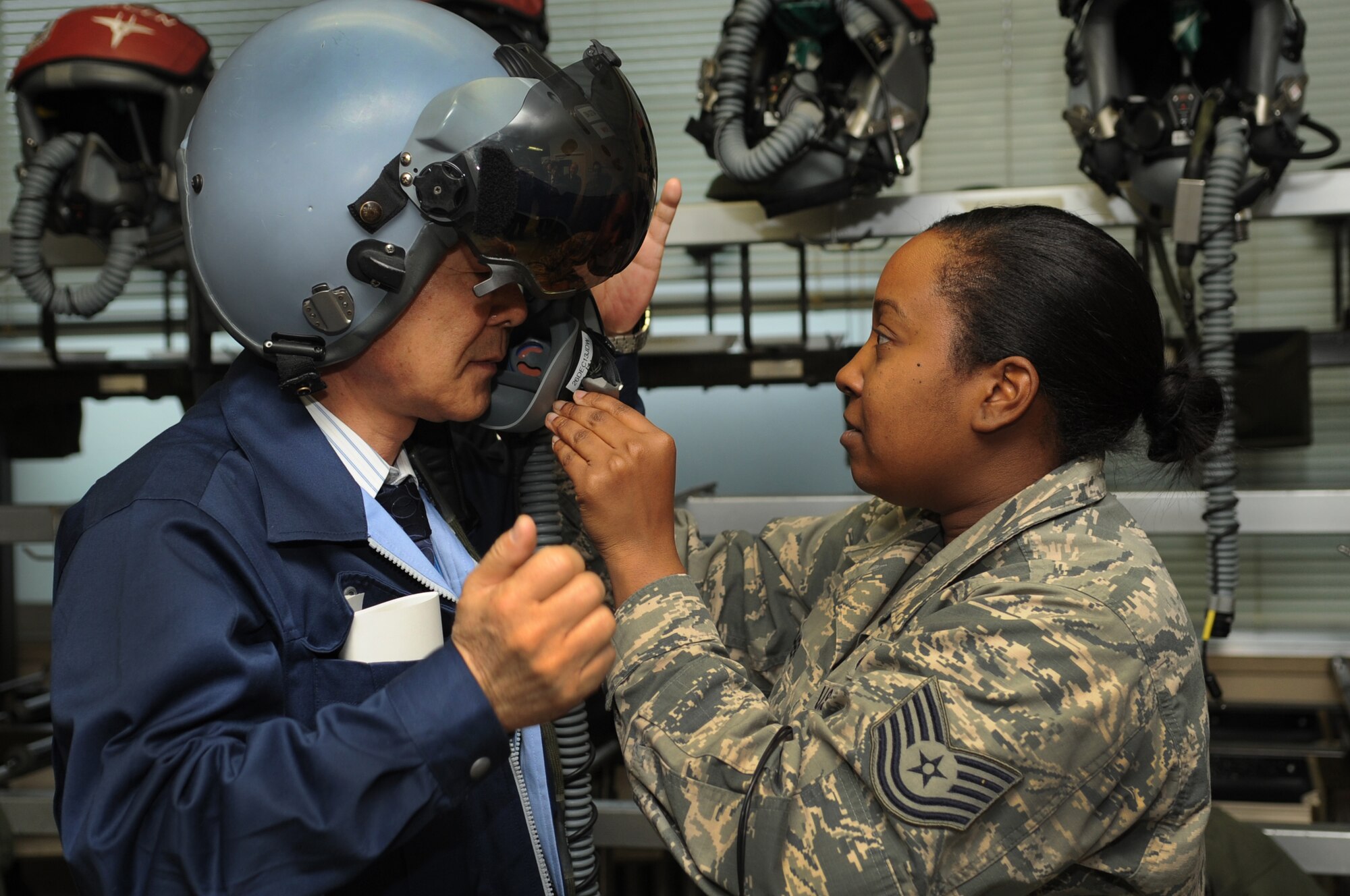 U.S. Air Force Tech. Sgt. Nicole Mather, 18th Operations Support Squadron aircrew flight equipment craftsman, helps Seiji Funamoto, a member of the Japanese Ministry of Defense, put on a joint helmeted mounted cueing system helmet during a life support demonstration on Komatsu Air Base, Japan, Dec. 10, 2013. As part of a week-long Aviation Training Relocation Program, members of Team Kadena held several demonstrations to promote interoperability between the two countries. (U.S. Air Force photo by Staff Sgt. Amber E. N. Jacobs)