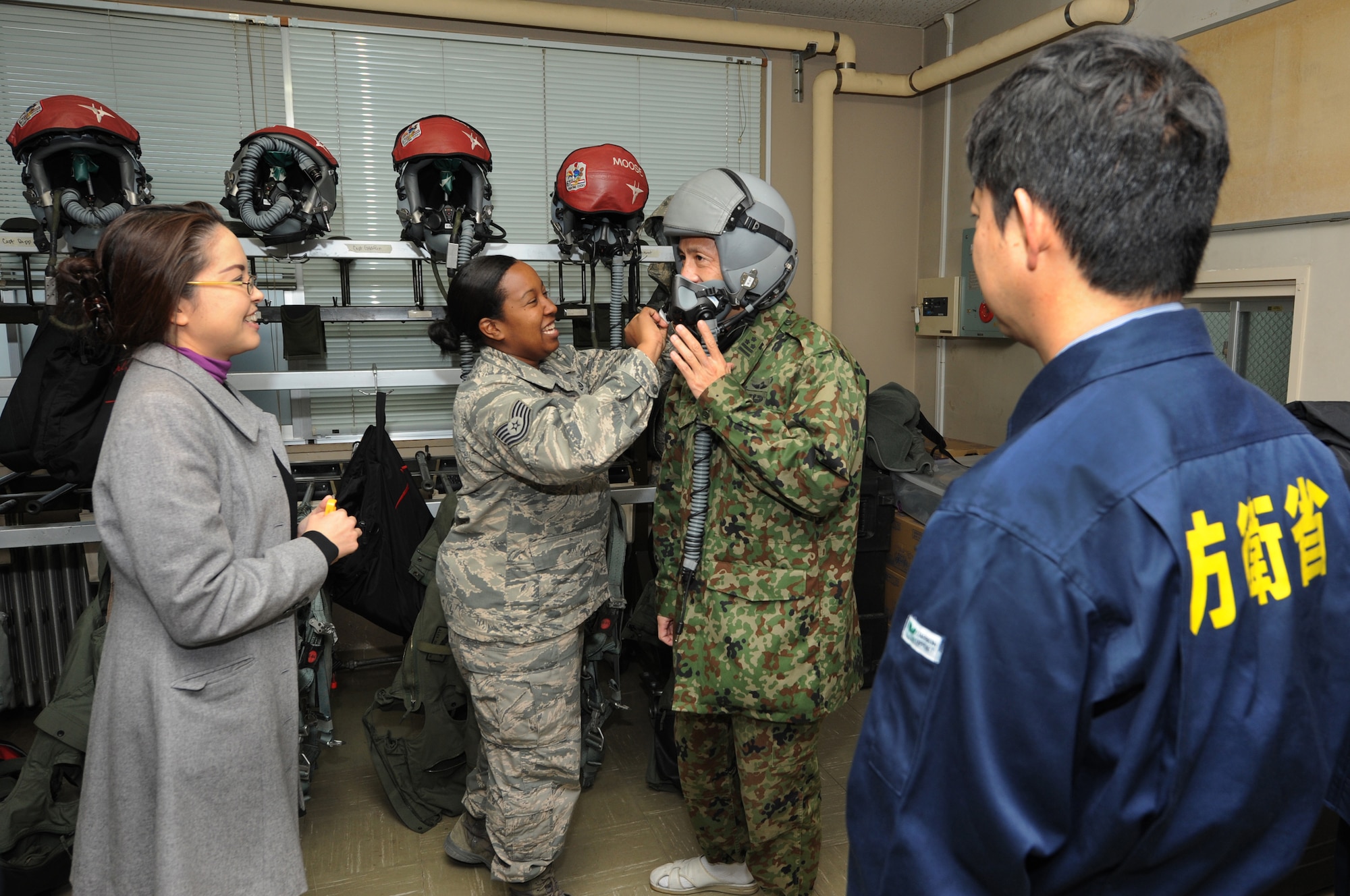 U.S. Air Force Tech. Sgt. Nicole Mather, 18th Operations Support Squadron aircrew flight equipment craftsman, helps Japanese Ground Self Defense Force Col. Koichiro Kaji, defense advisor, put on a HGU-55P helmet during a life support demonstration on Komatsu Air Base, Japan, Dec. 10, 2013. As part of a week-long Aviation Training Relocation Program, members of Team Kadena held several demonstrations to promote interoperability between the two countries. Mather explained the difference between the two helmets that pilots use when they fly and how vital they are to keeping the pilots mission capable. (U.S. Air Force photo by Staff Sgt. Amber E. N. Jacobs)