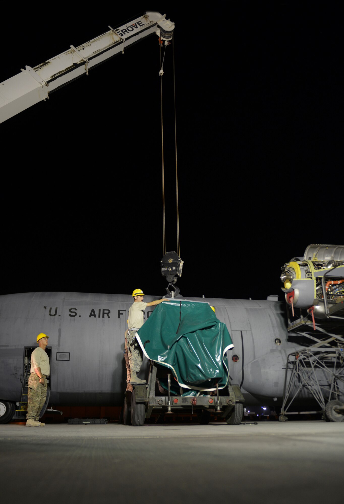 Senior Airman Michael Johnson (right) from the 379th Expeditionary Aircraft Maintenance Squadron, 746th Expeditionary Aircraft Maintenance Unit propulsion flight, aligns a C-130 engine on to an engine stand as Staff Sgt. Andrew McConkay, 557th Expeditionary Red Horse Squadron heavy equipment operator, looks on at the 379th Air Expeditionary Wing, Southwest Asia, Dec. 11, 2013. The 557th ERHS supported the engine swap by providing the crane and personnel to hoist the engine out and install the new engine. The combined efforts contributed to the engine being changed out in 12 hours and the aircraft ready to fly on schedule. Johnson is deployed from Keesler Air Force Base, Miss., and a Mobile, Ala., native. McConkay is deployed from Nellis Air Force Base, Nev., and a Salt Lake City native. (U.S. Air Force photo/Master Sgt. David Miller)