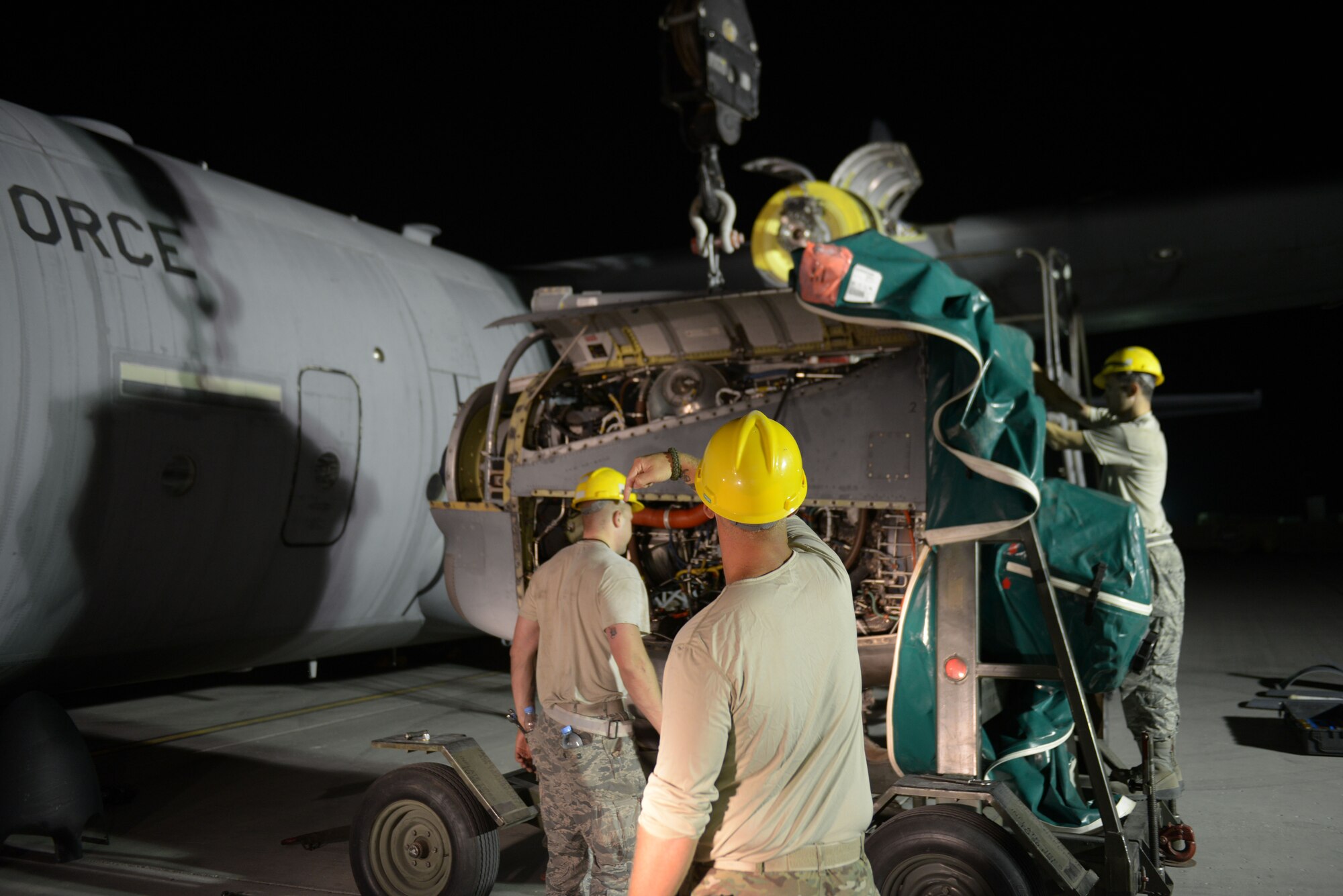 Staff Sgt. Andrew McConkay gives commands to Staff Sgt. Daniel Fox, 557th Expeditionary Red Horse Squadron heavy equipment operators as he operates a crane during a C-130 engine swap by members of the 379th Expeditionary Aircraft Maintenance Squadron, 746th Expeditionary Aircraft Maintenance Unit propulsion flight, at the 379th Air Expeditionary Wing, Southwest Asia, Dec. 11, 2013. The 557th ERHS provided short notice support for the engine swap by supplying the crane and personnel to hoist the engine out and install the new engine. The combined efforts contributed to the engine being swapped in 12 hours and the aircraft ready to fly on schedule. McConkay is deployed from Nellis Air Force Base, Nev., and a Salt Lake City native. (U.S. Air Force photo/Master Sgt. David Miller)