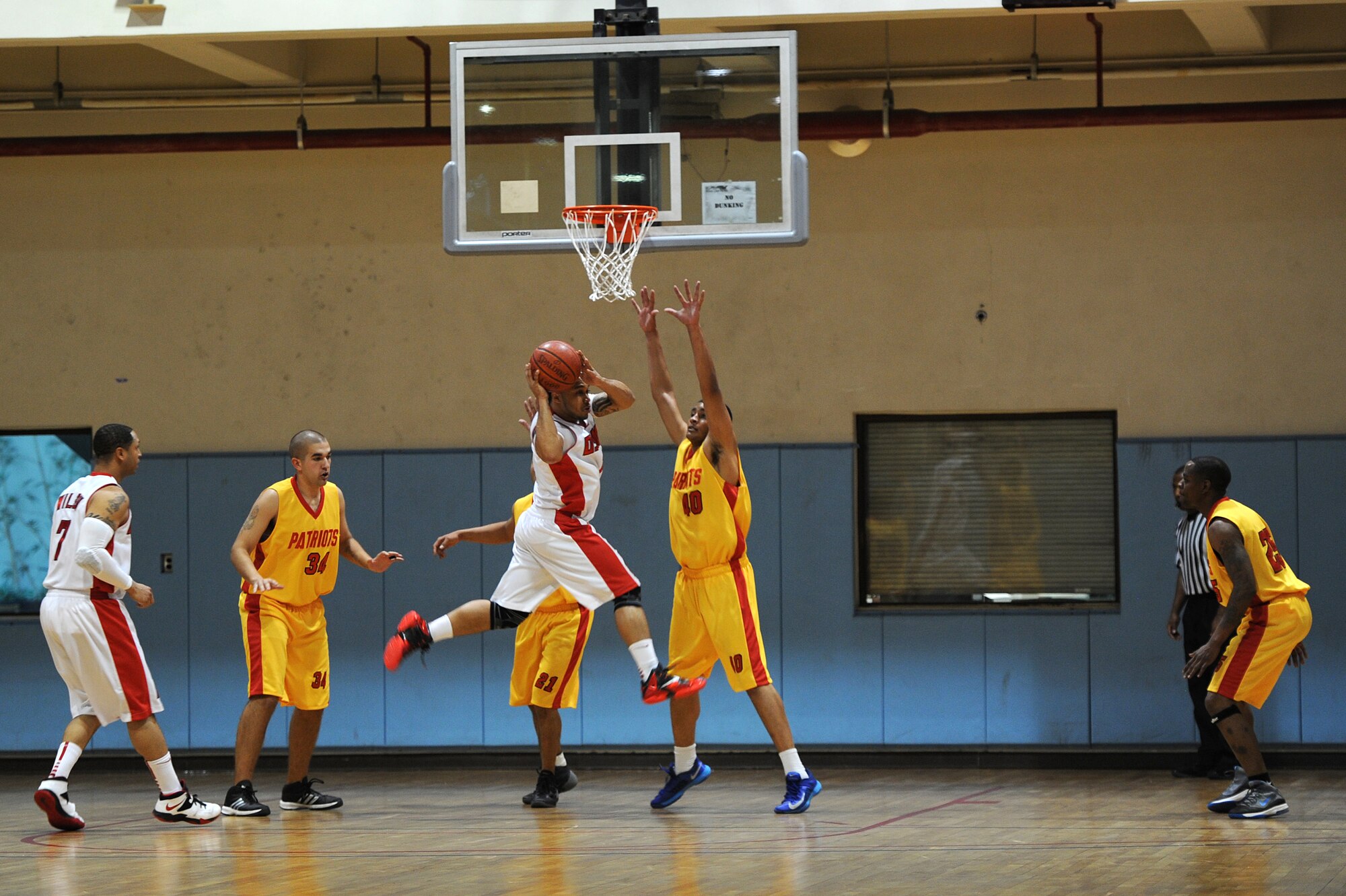 A member of the Osan basketball team jumps through two defenders while attempting to score two points during the Pacific Holiday Basketball Tournament at Osan Air Base, Republic of Korea, Dec. 12, 2013. The tournament is open to all Pacific Air Force teams. (U.S. Air Force photo/Staff Sgt. Emerson Nuñez)