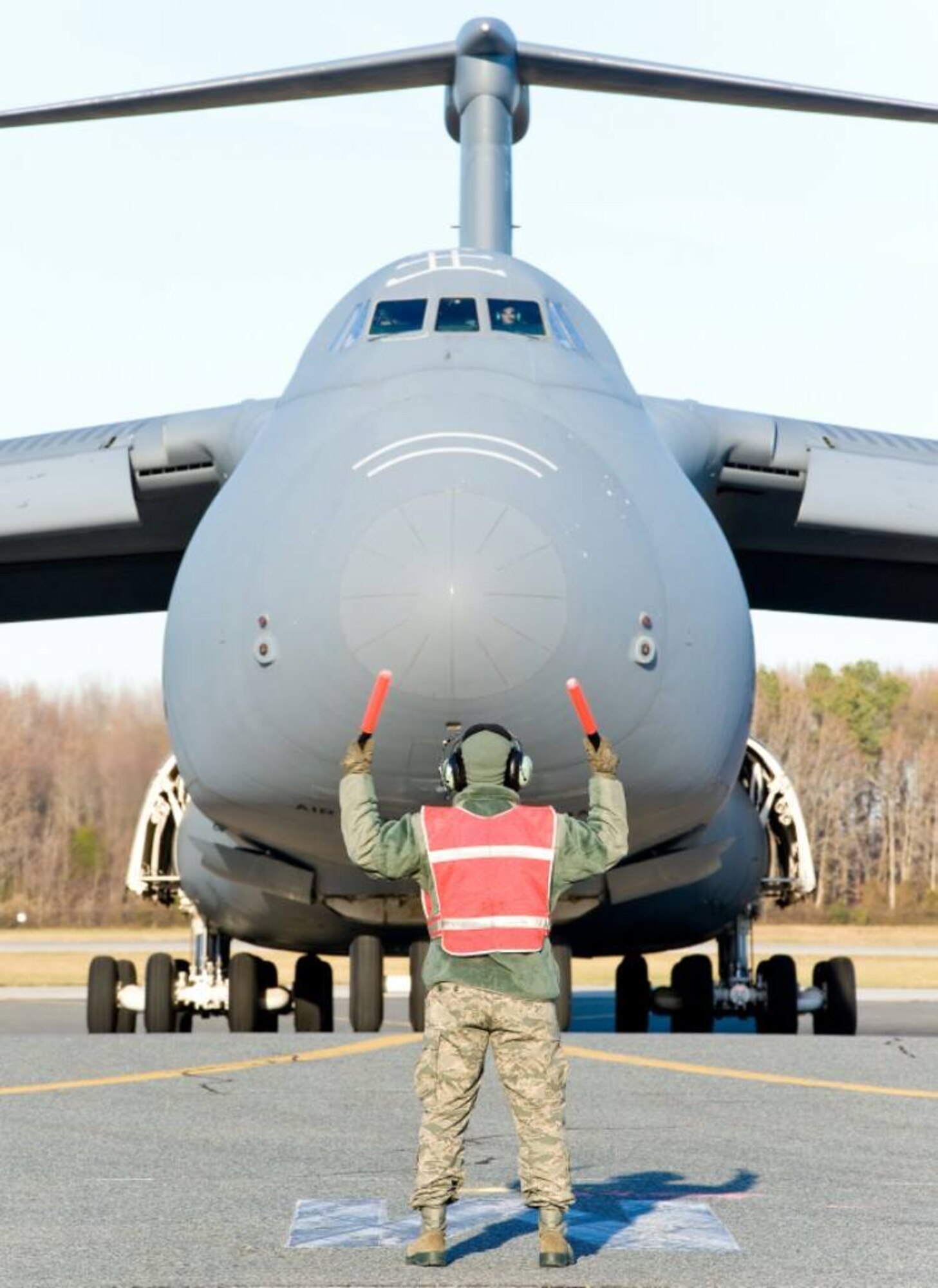 Staff Sgt. Heath Hackwell, 436th Aircraft Maintenance Squadron dedicated crew chief, marshals in C-5M Super Galaxy tail number 85-0008 onto its parking spot Dec. 13, 2013, at Dover Air Force Base, Del. This aircraft is the 14th to arrive of the total 18 C-5Ms Dover AFB is scheduled to receive. (U.S. Air Force photo/Roland Balik)