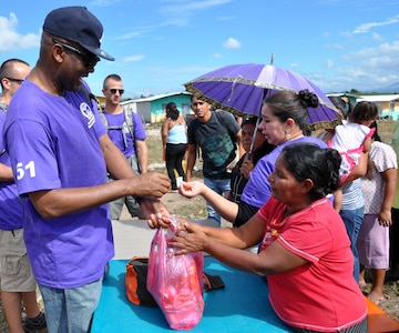 U.S. Army Command Sgt. Maj. Valmond Martin delivers a pack of food to a family in need in the village of Ajuterique in the Department of Comayagua, Honduras, during the 51st Joint Task Force-Bravo chapel hike, Dec. 14, 2013.  The Task Force members hiked three miles to the village to deliver more than 100 packs of food to families in the community, and then spent the remainder of their time working on a housing project in Ajuterique, doing manual labor to help build homes for families.  (U.S. Air Force photo by Capt. Zach Anderson)