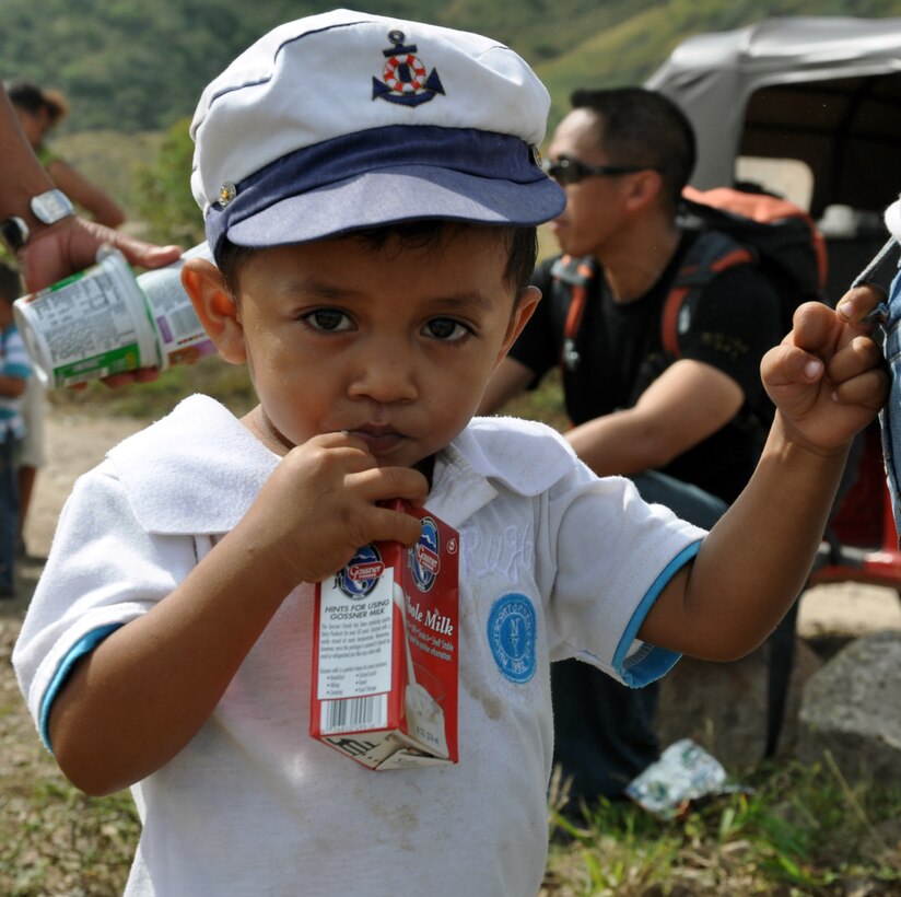 A young Honduran boy enjoys milk that was delivered by members of Joint Task Force-Bravo during the 51st JTF-Bravo Chapel Hike, Dec. 14, 2013.  Members of Joint Task Force-Bravo hiked three-miles to the village of Ajuterique in the Department of Comayagua, Honduras, to deliver more than 100 packs of food to families in need..  The Task Force members then spent the remainder of their time working on a housing project in Ajuterique, doing manual labor to help build homes for families.  (U.S. Air Force photo by Capt. Zach Anderson)