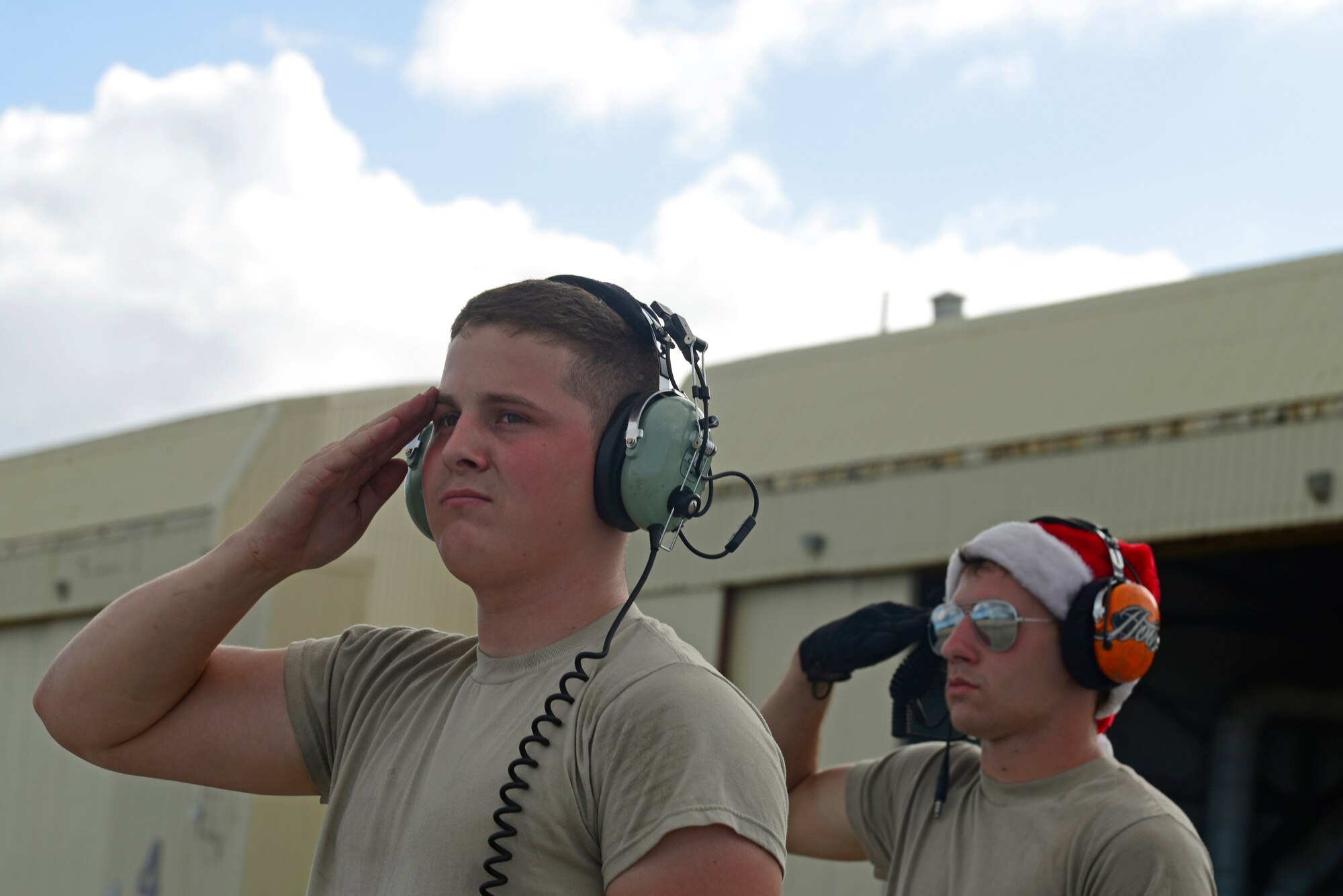 Airman 1st Class Nathan Judd (left), an electrical and environmental specialist , and Airman 1st Class Stephen Strapp, a crew chief, both assigned to the 374th Aircraft Maintenance Squadron, Yokota Air Base, Japan, salute a C-130H aircraft as it taxis before an airdrop mission during Operation Christmas Drop at Andersen Air Force Base, Guam, Dec. 11, 2013. This year marks the 62nd year of Operation Christmas Drop, which began in 1952, making it the world's longest running airdrop mission. Every December, C-130 Hercules crews from the 374th Airlift Wing at Yokota Air Base, Japan, partner with the 36th Wing at Andersen Air Force Base, Guam, to airlift food, supplies and toys to islanders throughout Micronesia. (U.S. Air Force photo by 2nd Lt. Jake Bailey/Released)