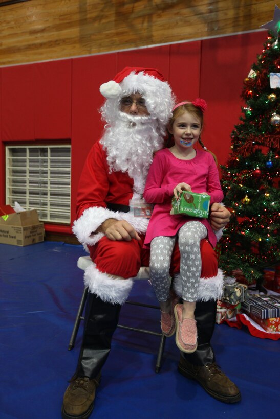 Alex G. Skutch, daughter of Maj. John P. Skutch, the logistics officer for the Command Element, 31st MEU, and a native to New York,  gets a present from Santa Claus during the 31st Marine Expeditionary Unit’s Christmas party at the House of Pain gymnasium here, Dec. 12. Santa Claus appeared at the party to pass out presents and take pictures with the children. The event provided an opportunity for the Marines and their families to spend time together, foster camaraderie and enjoy the holiday spirit. The 31st MEU is the Marine Corps’ force in readiness in the Asia-Pacific region and is the only continuously forward-deployed MEU.