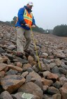 Wilmington District civil engineer Zack Nichols uses a probe to check the soil surface under a layer of riprap for any signs of erosion during the annual dam safety inspection at Falls Dam in Raleigh. (USACE photo by Hank Heusinkveld)