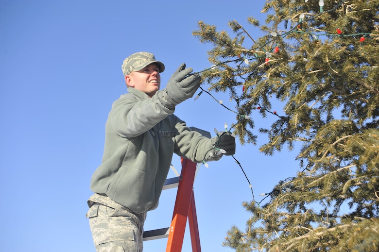 Senior Airman Ryan Clancey, 460th Space Communications Squadron, strings lights across a Christmas tree, Dec. 9, 2013, on Buckley Air Force Base, Colo. Clancey decorated the tree in memory of Kristopher Mansfield, a former 460th SCS Airman who was killed by a drunk driver. Friends and family decorate the tree in celebration of Mansfield’s life and what he meant to the squadron. (U.S. Air Force photo by Airman 1st Class Samantha Saulsbury/Released)