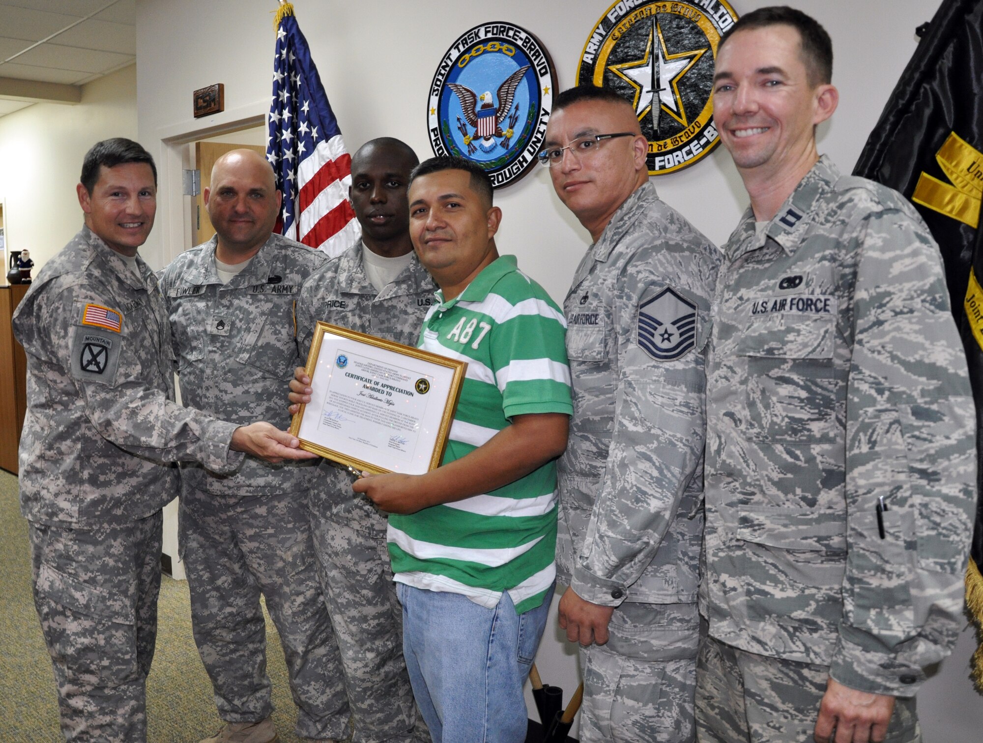 Lt. Col. Alan McKewan, Commander of Joint Task Force-Bravo's Army Forces Battalion, presents a certificate of appreciation to Jose Adalberto Mejia for his actions in helping to assist at the scene of a vehicle accident, Soto Cano Air Base, Honduras, Dec. 16, 2013. On the evening of Dec. 11, 2013, Adalberto Mejia was driving a taxi with U.S. Air Force Capt. Allen Bear, U.S. Air Force Master Sgt. Michael Batres, U.S. Army Staff Sgt. John Fowler and U.S. Army Sgt. Willie Price (pictured) riding as passengers when the men witnessed a vehicle striking a cow that had wandered onto the road. The vehicle flipped upside down and came to rest in a ditch. The five men came to the aid of the driver of the overturned vehicle, pulling him from the wreckage and then loading him into the taxi to transport him to receive medical treatment. (U.S. Air Force photo by Capt. Zach Anderson)