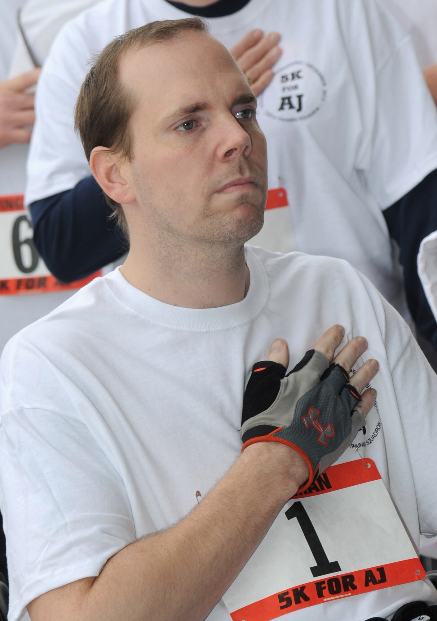 Master Sgt. Albert “AJ” Jackson, 335th Training Squadron, places his hand over his heart while the National Anthem plays during the “5K for AJ” benefit run Dec. 14, 2013, Keesler Air Force Base, Miss. The event, organized by the 335th TRS “Bulls,” was held to raise money for AJ, who was paralyzed from a medical procedure.  (U.S. Air Force photo by Kemberly Groue)