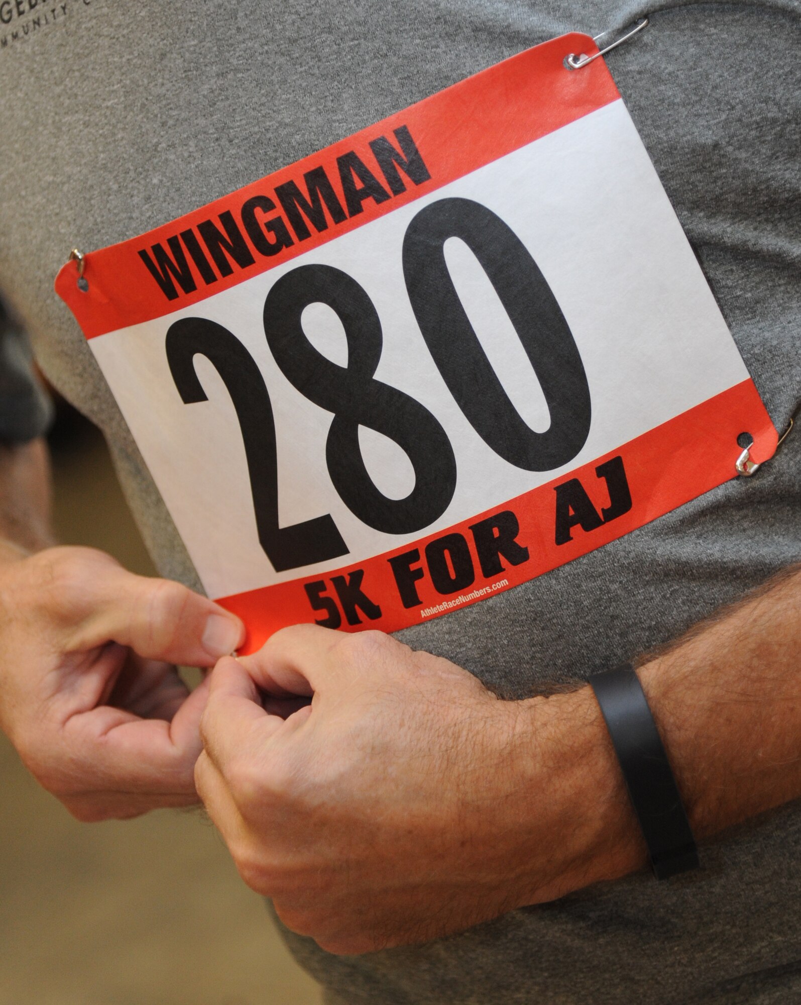 Staff Sgt. Charles Breeden, 335th Training Squadron, secures his number during the “5K for AJ” benefit run Dec. 14, 2013, Keesler Air Force Base, Miss. The 5K run was held to raise money for Master Sgt. Albert “AJ” Jackson, 335th TRS, who was paralyzed from a medical procedure. The event, organized by the 335th TRS “Bulls,” raised more than $15,700 to assist the family.  (U.S. Air Force photo by Kemberly Groue)