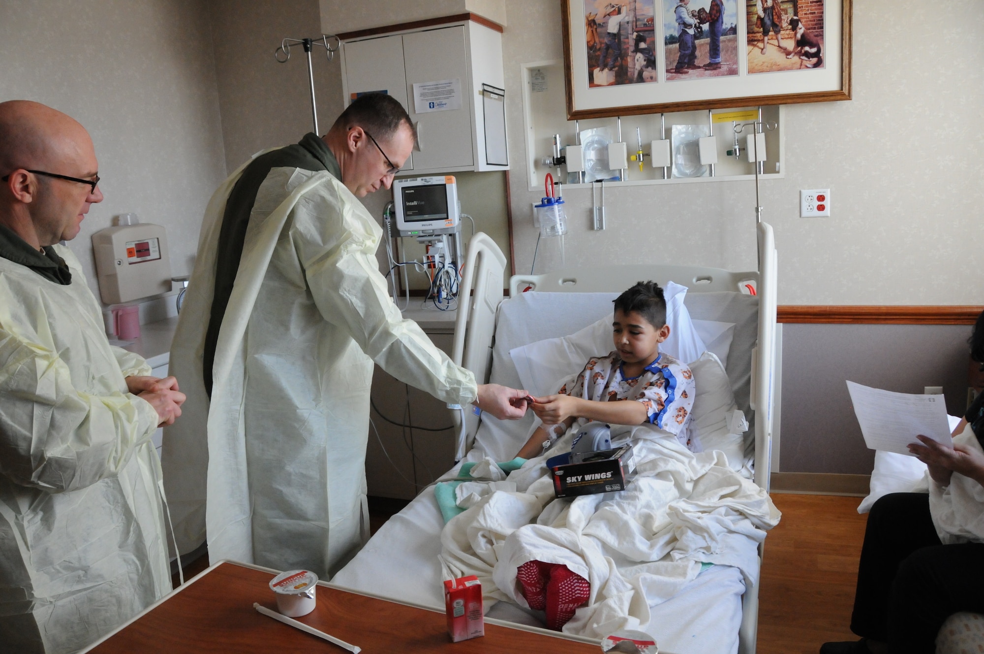 YOUNGSTOWN AIR RESERVE STATION, Ohio— Lieutenant Colonel John “Chinky” Kochansky, assistant deputy officer of the 757th Airlift Squadron (left), and Lieutenant Colonel Christopher Zwetzig, 910th Operations Group standards evaluation navigator, give a Toys for Tots coin to 11-year-old Ali. Ali also received a C-130 model and Air Force ball cap. Several YARS members visited the hospital to spread holiday cheer, passing out toys collected during the YARS-based Marine Corps Reserve Detachment-3 Maintenance Company’s Toys for Tots campaign, along with Air Force promotional items and wing patches. This year’s hospital visit marked the fourth consecutive December trip. (U.S. Air Force photo/Eric M. White)