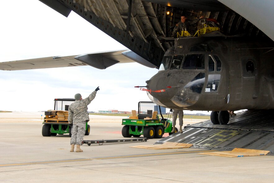 An Illinois Army National Guardsman directs a CH-47 Chinook exiting an Air Force C-17 Globemaster III at the Peoria Army Aviation Support Facility, Peoria, Ill., Nov. 26, 2013. The aircraft transported the helicopter back to the 2nd Battalion, 238th General Support Aviation Battalion from service in Afghanistan. (U.S. Air National Guard photo by Staff Sgt. Lealan C. Buehrer/Released)