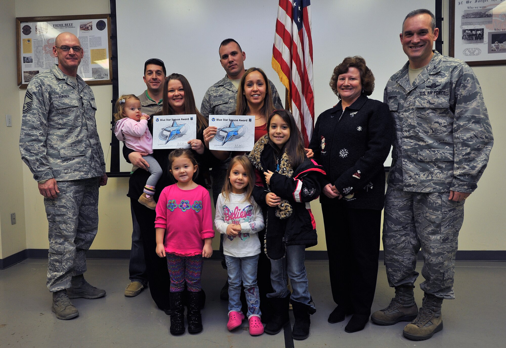 Col. Newberry, 92nd Air Refueling Wing commander, his wife, Jill, and Chief Master Sgt. Lance Turner, 92nd Medical Group superintendent, presents the Blue Star Spouse Award to Ms. Amber Meza and Ms. Jeannine Collins, at Fairchild Air Force Base, Wash., Dec. 13, 2013. Their husband's, Master Sgt. Eric Meza and Tech. Sgt. Ken Collins, both from the 92nd Civil Engineer Squadron, and their children, were present to help congratulate them.  These two dedicated 92nd CES spouses were presented the award for their innovation in setting up a key spouse office in the squadron and passionately connecting new Airmen and their families to the squadron.   Anyone interested in nominating someone for the Blue Star Spouse Award should contact their squadron commander. (U.S. Air Force photo by Staff Sgt. Veronica Montes)