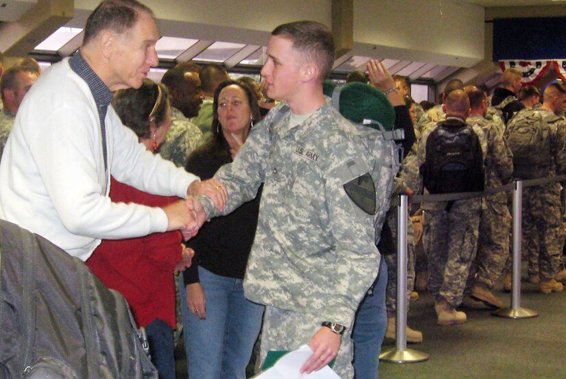Beginning Dec. 20, 2013, Soldiers will be eligible for expedited pre-flight screening, meaning they'll be able to get into the express line where they don't have to remove their shoes and belts or laptops from their baggage. Pictured here are Soldiers going through a non-expedited line. The man on the left is thanking a Soldier for his service. (U.S. Army photo by Sgt. 1st Class Damian Steptore/Released)