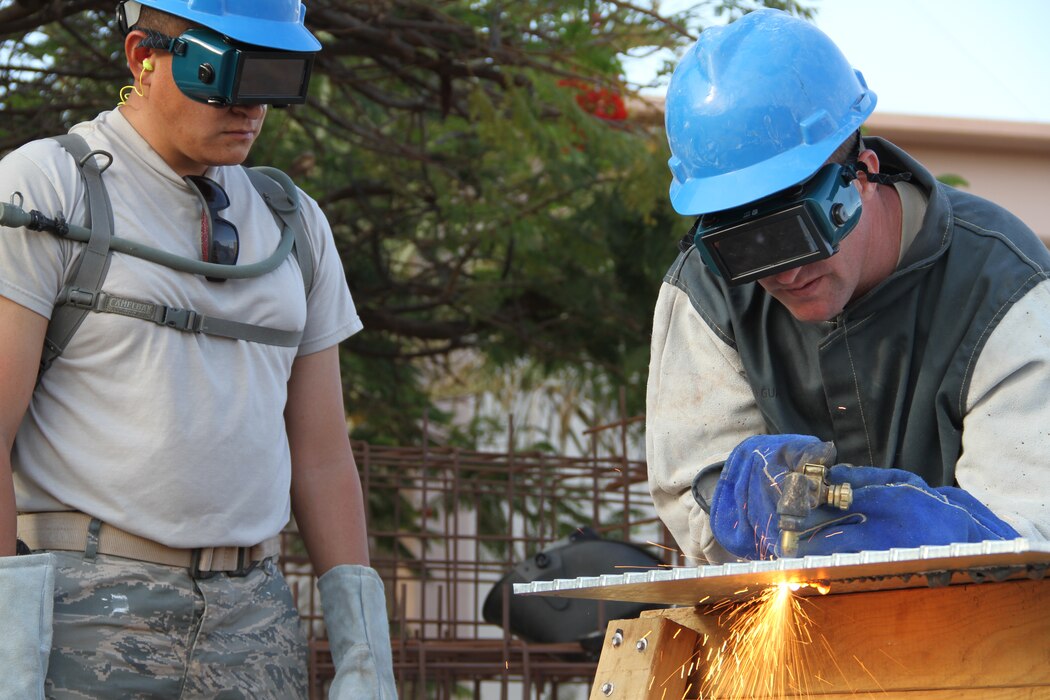 TSgt. Jared Webb looks on as SSgt. Merrell Brown cuts galvanized steel to use as a cover plate for piping at the Space Surveillance Network radar site in Exmouth, Western Australia. (Utah Air National Guard photo by CMSgt. Mark Savage/RELEASED)