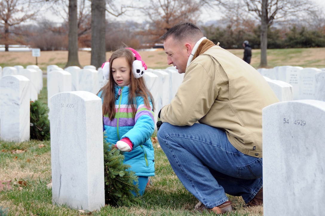 Marine Corps Maj. Daniel Smith and daughter, Kara Anne, lay a wreath at a gravesite at Arlington National Cemetery in northern Virginia, Dec. 14, 2013, as part of the 22nd annual “Wreaths Across America” event. U.S. Army photo by C. Todd Lopez