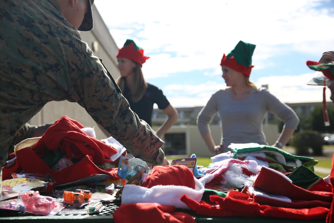 Samantha Cook-Watt, a life skills trainer with Marine Corps Community Services, and Haley Taricani, the readiness and deployment support manager with MCCS, hand out donated stocking stuffers along with the free trees given out to Marines, Sailors, and their families by Peltzer Pines Tree Farm aboard Marine Corps Air Station Miramar, Calif., Dec. 16. The donated trees were handed out to the service members and their families on a first come, first serve basis.