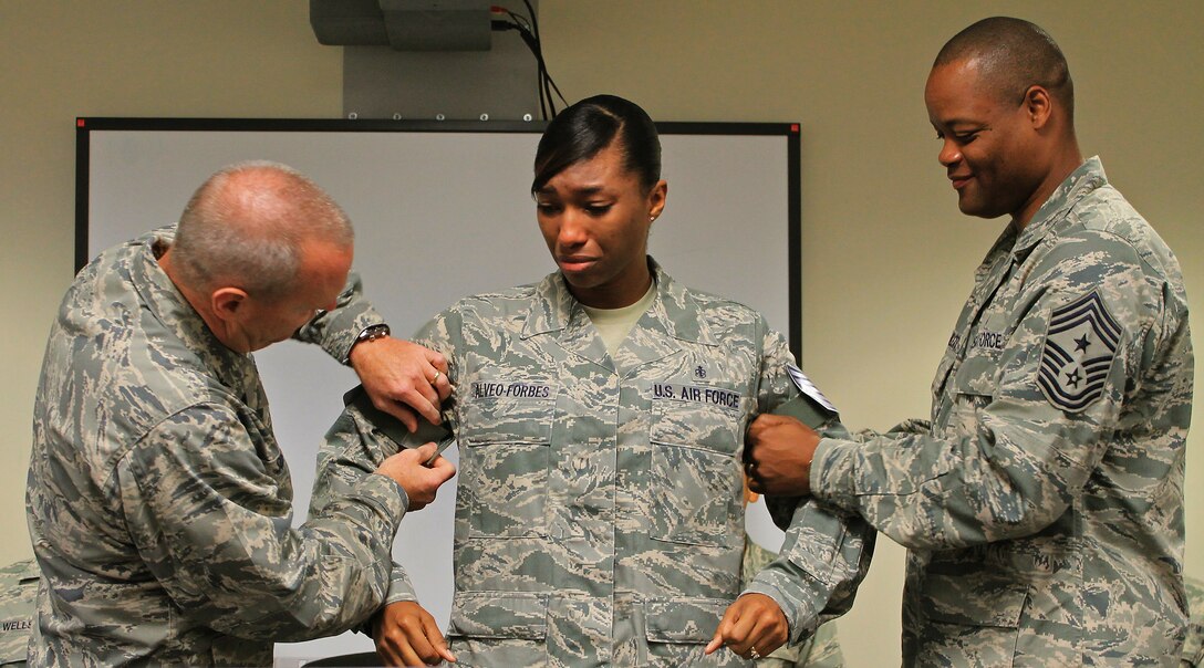 Col. Terry Scott, 15th Wing vice commander, left, and  Chief Master Sgt. Leslie Bramlett, 15th Wing command chief, right,  tacks new technical sergeant stripes on surprised Staff Sgt. Angela Alveo-Forbes, 535th Airlift Squadron, independent duty medical technician (middle), at the Joint Base Pearl Harbor-Hickam First Term Airman Center, Hawaii, Dec. 13. 2013. The Stripes for Exceptional Performers program allows major commands, field operating agencies, direct reporting unit commanders, and senior Air Force officers with large enlisted populations to select a limited number of Airmen with exceptional potential for promotion to the grades of staff sergeant through master sergeant.  (U.S. Air Force photo/Senior Airman Stoltz)