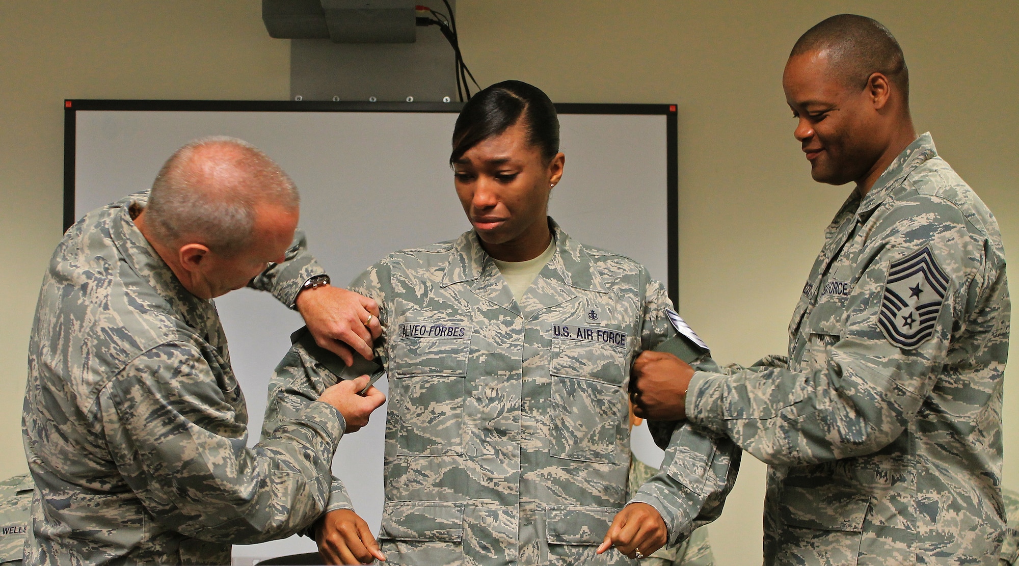 Col. Terry Scott, 15th Wing vice commander, left, and  Chief Master Sgt. Leslie Bramlett, 15th Wing command chief, right,  tacks new technical sergeant stripes on surprised Staff Sgt. Angela Alveo-Forbes, 535th Airlift Squadron, independent duty medical technician (middle), at the Joint Base Pearl Harbor-Hickam First Term Airman Center, Hawaii, Dec. 13. 2013. The Stripes for Exceptional Performers program allows major commands, field operating agencies, direct reporting unit commanders, and senior Air Force officers with large enlisted populations to select a limited number of Airmen with exceptional potential for promotion to the grades of staff sergeant through master sergeant.  (U.S. Air Force photo/Senior Airman Stoltz)