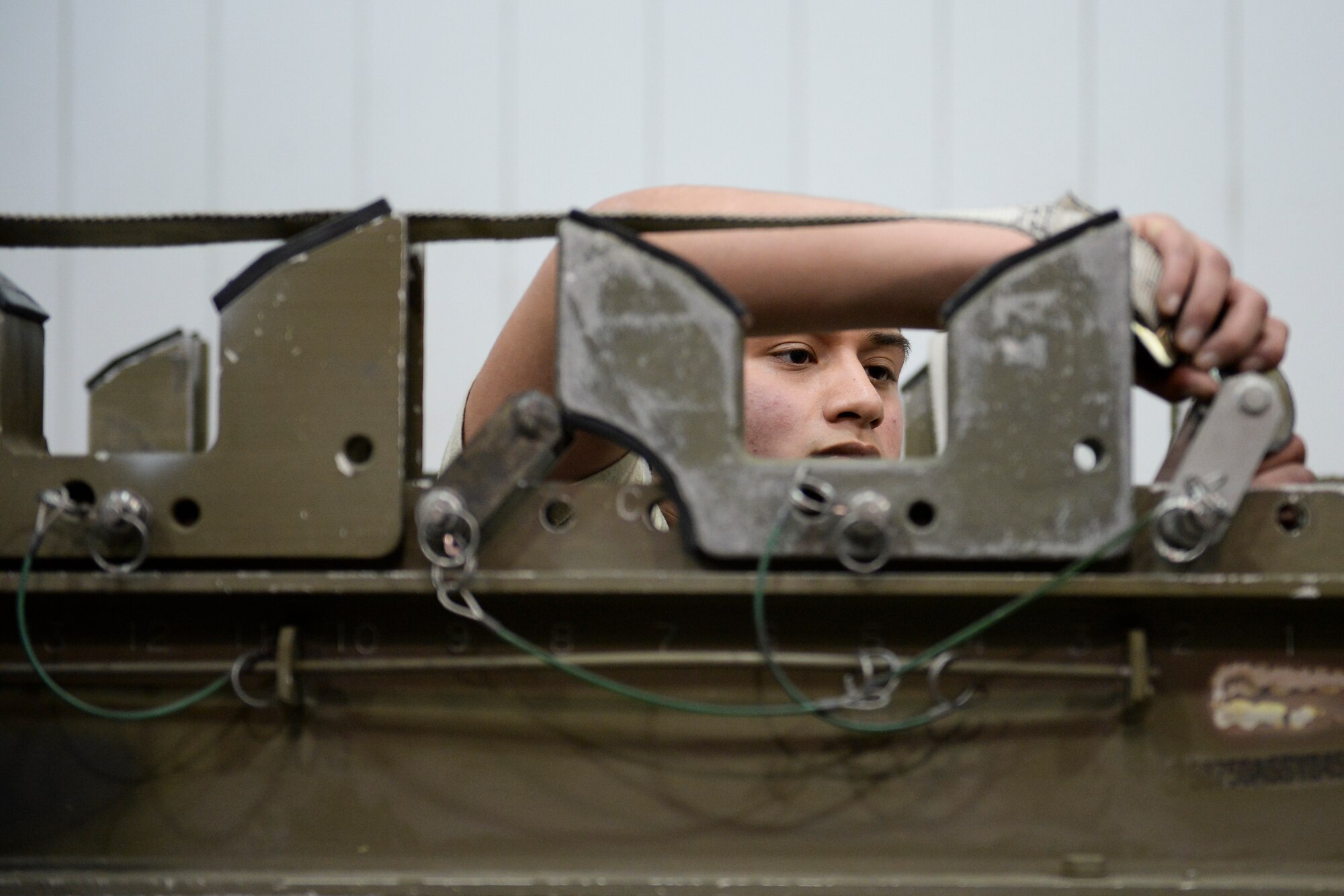 U.S. Air Force Airman 1st Class Uziel Huerta secures missile retaining straps on a 141 munitions trailer in an aircraft maintenance hangar during an annual load crew competition Dec. 13, 2013, Eielson Air Force Base, Alaska. The competition pitted two of Eielson's top performing load crews against each other to see who would earn this year's load crew of the year award. The winning team is announced at the 354th Fighter Wing annual awards banquet. (U.S. Air Force photo by Airman 1st Class Peter Reft/Released)