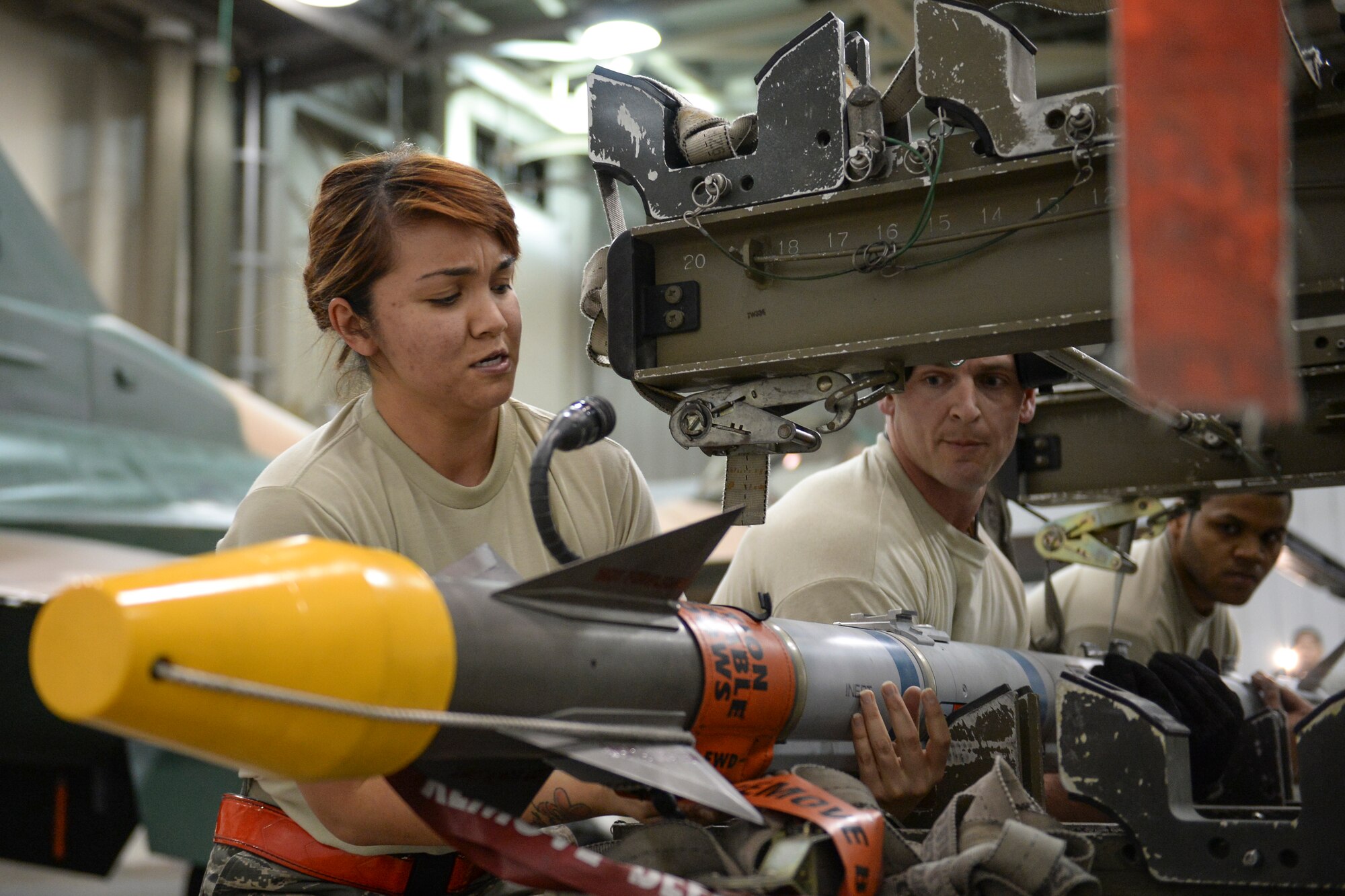 U.S. Air Force Senior Airman Alexa Donithan, Staff Sgt. Brett Dallinger and Senior Airman Ralphy Rosado, 354th Aircraft Maintenance Squadron weapons load crew, lift an AIM-9 Sidewinder missile off a weapon trailer during an annual load crew competition Dec. 13, 2013, Eielson Air Force Base, Alaska.  The competition highlighted Eielson's top weapons load crew members who have achieved outstanding performance and safety records throughout the year. (U.S. Air Force photo by Airman 1st Class Peter Reft/Released)