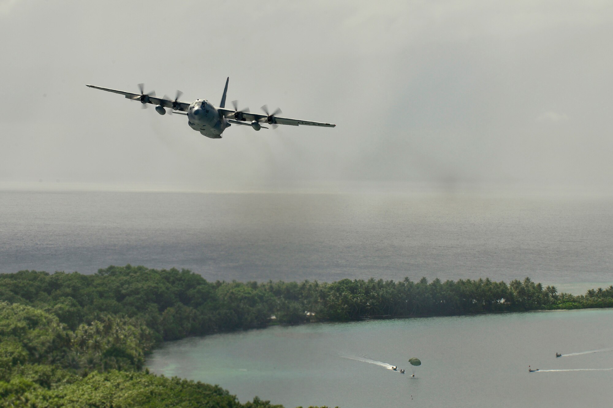 Micronesian islanders boat out to falling supplies airdropped from a C-130 Hercules during Operation Christmas Drop near Andersen Air Force Base, Guam, Dec. 16, 2013. This year marks the 62nd year of Operation Christmas Drop, which began in 1952, making it the world's longest running airdrop mission. Every December, C-130 Hercules crews from the 374th Airlift Wing at Yokota Air Base, Japan, partner with the 36th Wing at Andersen Air Force Base, Guam, to airlift food, supplies and toys to islanders throughout Micronesia. (U.S. Air Force photo by 2nd Lt. Jake Bailey/Released)