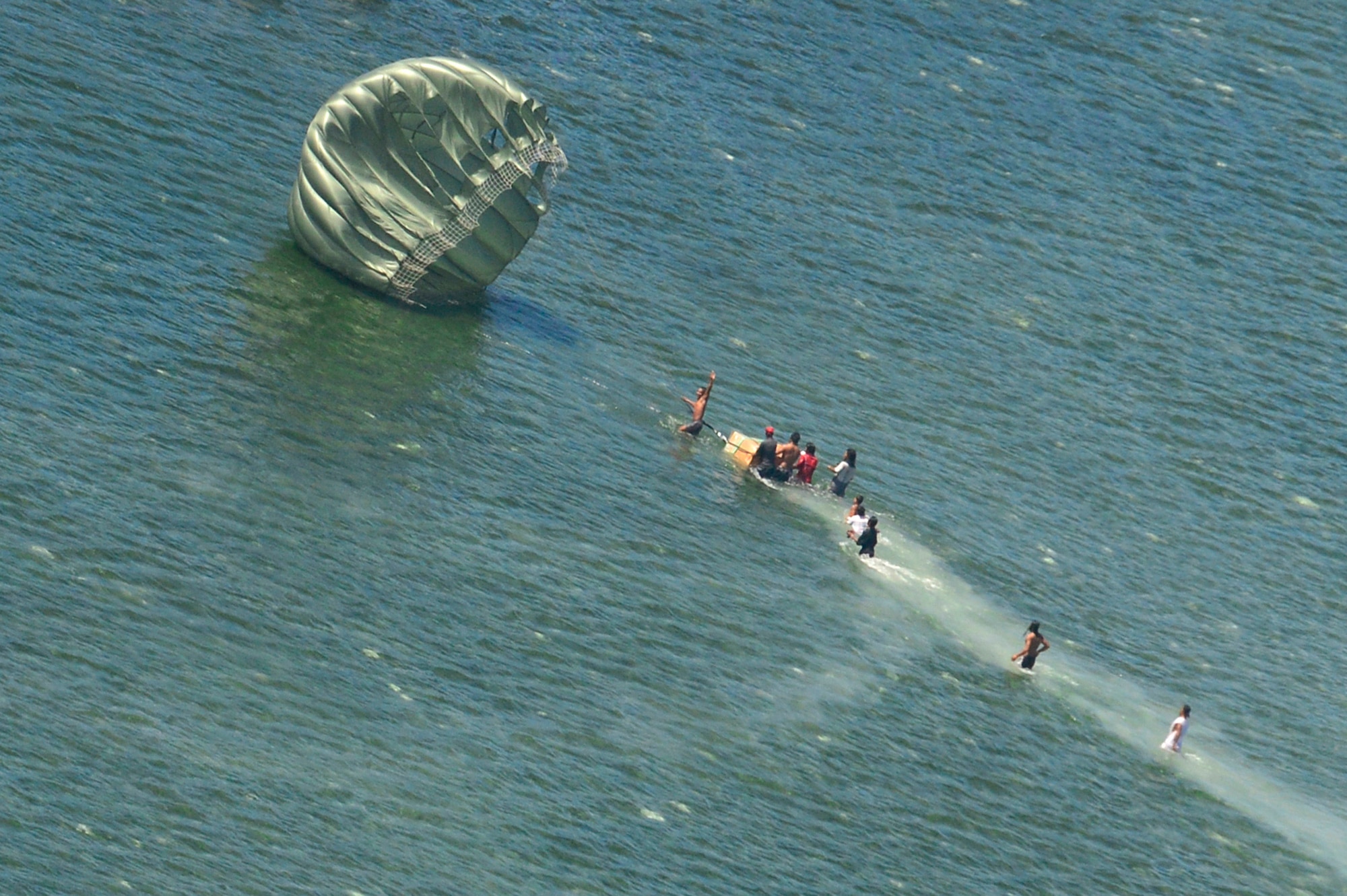 Micronesian islanders receive supplies airdropped from a C-130 Hercules near Andersen Air Force Base, Guam, Dec. 16, 2013. This year marks the 62nd year of Operation Christmas Drop, which began in 1952, making it the world's longest running airdrop mission. Every December, C-130 Hercules crews from the 374th Airlift Wing at Yokota Air Base, Japan, partner with the 36th Wing at Andersen Air Force Base, Guam, to airlift food, supplies and toys to islanders throughout Micronesia. (U.S. Air Force photo by 2nd Lt. Jake Bailey/Released)