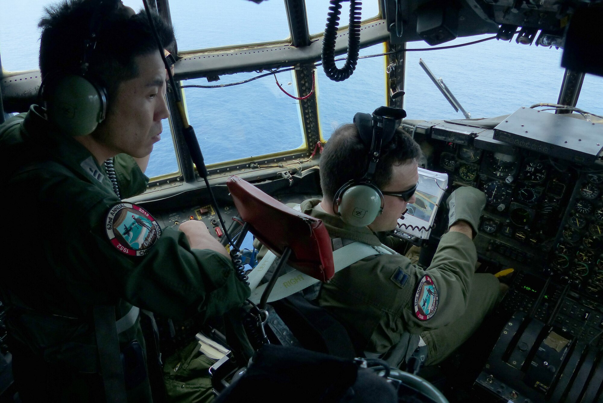 A pilot from the Japan Air Self-Defense Force observes as Capt. Travis Patton, a pilot assigned to the 36th Airlift Squadron, Yokota Air Base, Japan, flies an airdrop mission near Pakin, Federated States of Micronesia, during Operation Christmas Drop Dec. 15, 2013. This year marks the 62nd year of Operation Christmas Drop, which began in 1952, making it the world's longest running airdrop mission. Every December, C-130 Hercules crews from the 374th Airlift Wing at Yokota Air Base, Japan, partner with the 36th Wing at Andersen Air Force Base, Guam, to airlift food, supplies and toys to islanders throughout Micronesia. (U.S. Air Force photo by 2nd Lt. Jake Bailey/Released)