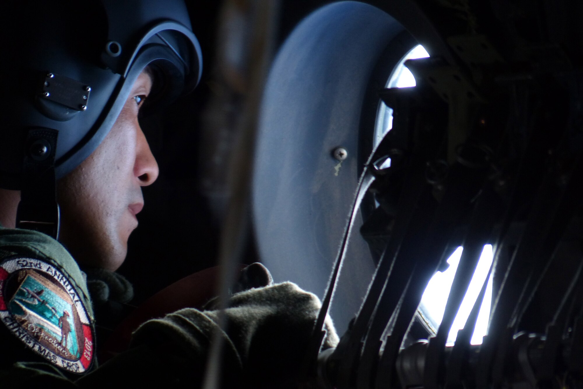 A Japan Air Self-Defense Force loadmaster looks from a C-130H aircraft window during an airdrop mission during Operation Christmas Drop Dec. 15, 2013. This year marks the 62nd year of Operation Christmas Drop, which began in 1952, making it the world's longest running airdrop mission. Every December, C-130 Hercules crews from the 374th Airlift Wing at Yokota Air Base, Japan, partner with the 36th Wing at Andersen Air Force Base, Guam, to airlift food, supplies and toys to islanders throughout Micronesia. (U.S. Air Force photo by 2nd Lt. Jake Bailey/Released)