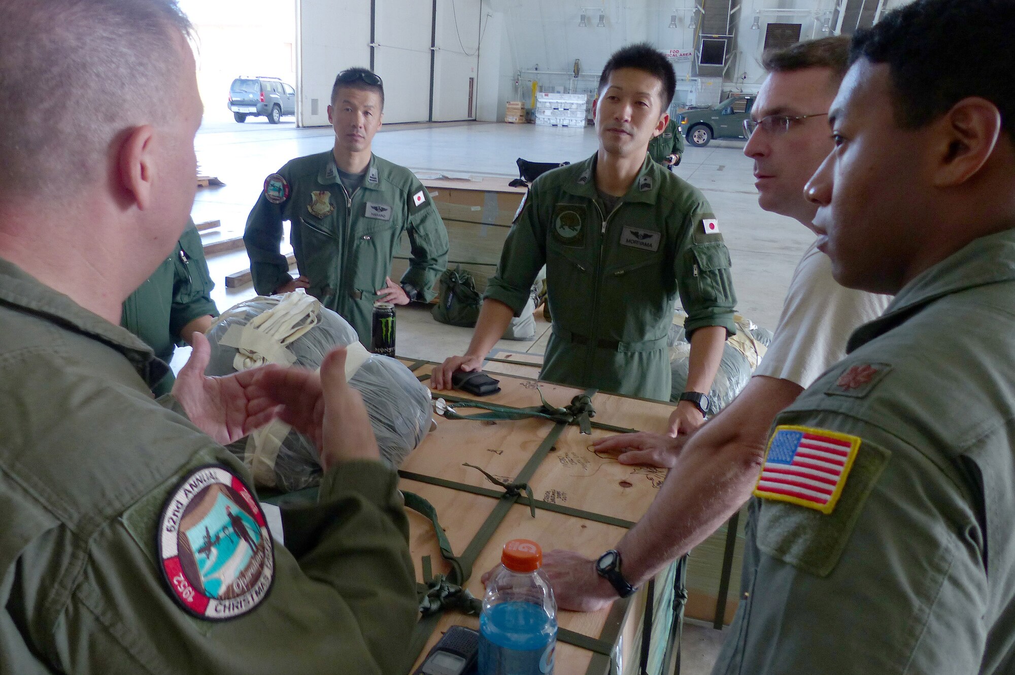 Airmen from the 374th Airlift Wing, Yokota Air Base, Japan, discuss low-cost, low-altitude rigging techniques with aircrew members from the Japan Air Self-Defense Force at Andersen Air Force Base, Guam, Dec. 14, 2013. This year marks the 62nd year of Operation Christmas Drop, which began in 1952, making it the world's longest running airdrop mission. Every December, C-130 Hercules crews from the 374th Airlift Wing at Yokota Air Base, Japan, partner with the 36th Wing at Andersen Air Force Base, Guam, to airlift food, supplies and toys to islanders throughout Micronesia. (U.S. Air Force photo by 2nd Lt. Jake Bailey/Released)