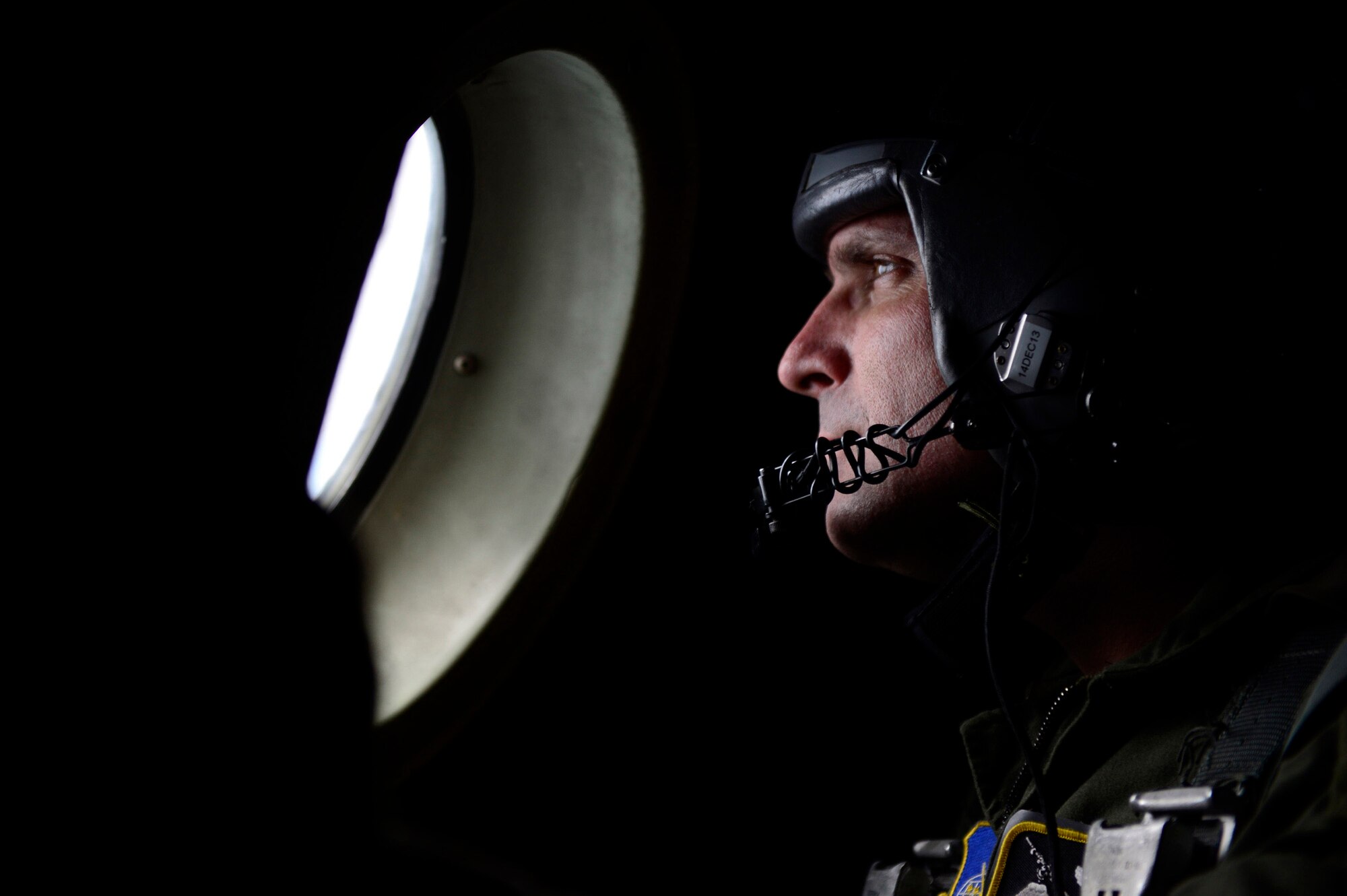 Master Sgt. Eric Gaul, a loadmaster assigned to the 36th Airlift Squadron, Yokota Air Base, Japan, looks from a C-130H window on approach to an objective in the Federated States of Micronesia during Operation Christmas Drop, Dec. 13, 2013. This year marks the 62nd year of Operation Christmas Drop, which began in 1952, making it the world's longest running airdrop mission. Every December, C-130 Hercules crews from the 374th Airlift Wing at Yokota Air Base, Japan, partner with the 36th Wing at Andersen Air Force Base, Guam, to airlift food, supplies and toys to islanders throughout Micronesia. (U.S. Air Force photo by 2nd Lt. Jake Bailey/Released)