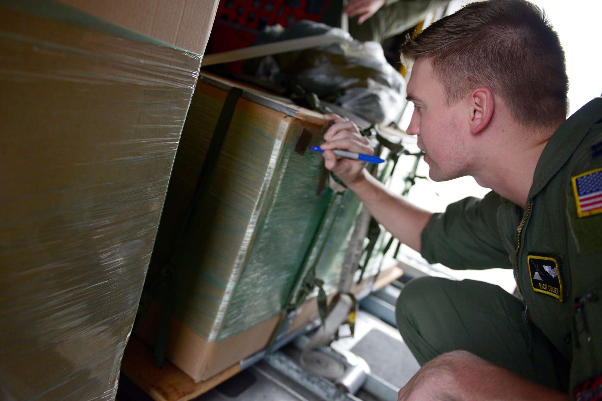 Capt. Rick Culver, a navigator assigned to the 36th Airlift Squadron, Yokota Air Base, Japan, signs an airdrop bundle with a holiday greeting before an airdrop mission during Operation Christmas Drop at Andersen Air Force Base, Guam, Dec. 13, 2013. This year marks the 62nd year of Operation Christmas Drop, which began in 1952, making it the world's longest running airdrop mission. Every December, C-130 Hercules crews from the 374th Airlift Wing at Yokota Air Base, Japan, partner with the 36th Wing at Andersen Air Force Base, Guam, to airlift food, supplies and toys to islanders throughout Micronesia. (U.S. Air Force photo by 2nd Lt. Jake Bailey/Released)