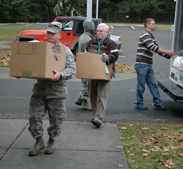 Staff Sgt. Miguel Rodriguez, 446th Aircraft Maintenance Squadron, helps carry boxes of food into 446th Airman and Family Readiness Center, with Carl Supplee, director of the 446th A&FRC, right behind him. Thirty-two boxes of food were donated to the 446th Airlift Wing by the Central Pierce County Fire Department. For the past eight years, these firefighters have supported families in need throughout Pierce County by giving them boxes full of food. (U.S. Air Force Reserve photo by Sandra Pishner)