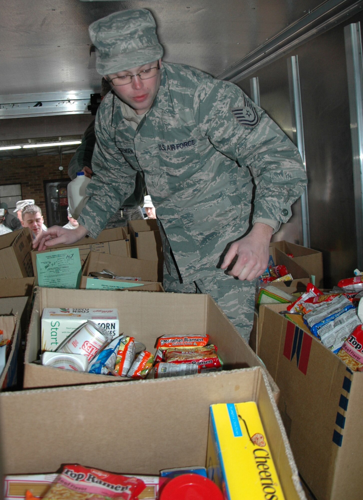 Tech. Sgt. Michael Christensen, 446th Aircraft Maintenance Squadron, organizes boxes of food as other Reservists and Pierce County Firefighters load up the goods for the annual holiday food baskets.  Thirty-two boxes of food were donated to the 446th Airlift Wing by the Central Pierce County Fire Department. For the past eight years, these firefighters have supported families in need throughout Pierce County by giving them boxes full of food. (U.S. Air Force Reserve photo by Sandra Pishner)