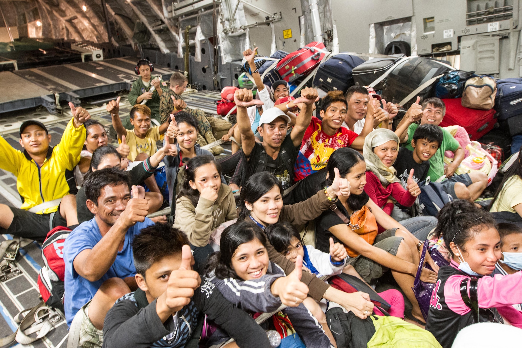 Displaced residents from Tacoloban, Philippines, give thumbs up after boarding a C-17 Globemaster III Nov. 17, 2013, for an evacuation flight to Manila following Super Typhoon Haiyan. The inherent flexibility and performance of the C-17 force improves the ability of the total airlift system to fulfill air mobility requirements in support of Operation Damayan. (U.S. Air Force Photo/Staff Sgt. Ramon Brockington)