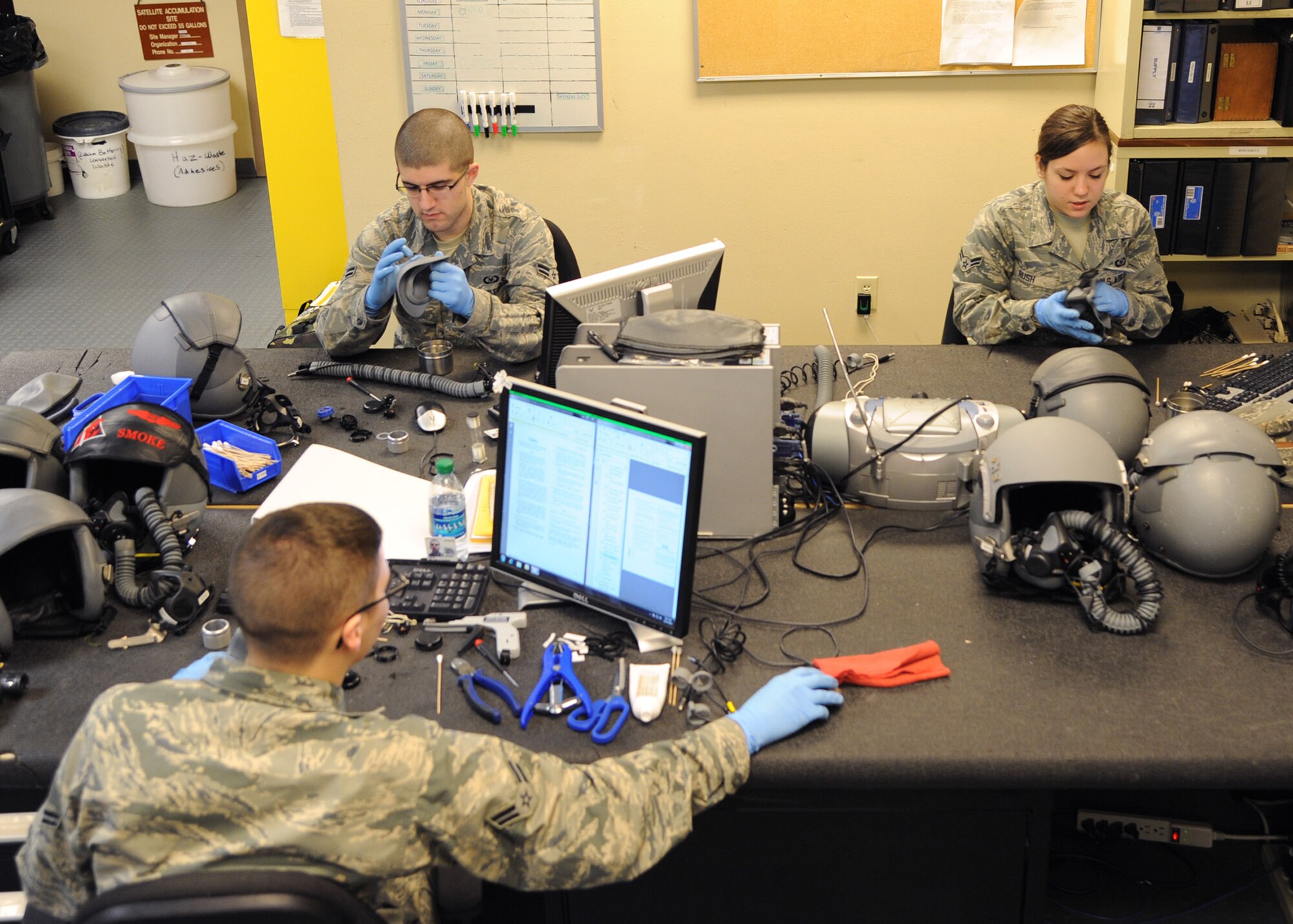 Airmen from the 2nd Operational Support Squadron Aircrew Flight Equipment shop, perform a 30- day inspection of HGU-55P helmets on Barksdale Air Force Base, La., Dec. 17, 2013. The helmet provides pilots and officers with basic head protection, sound attenuation, symbology, weapons cueing and a communication system for aircrew personnel. (U.S. Air Force photo/Senior Airman Joseph A. Pagán Jr.)
