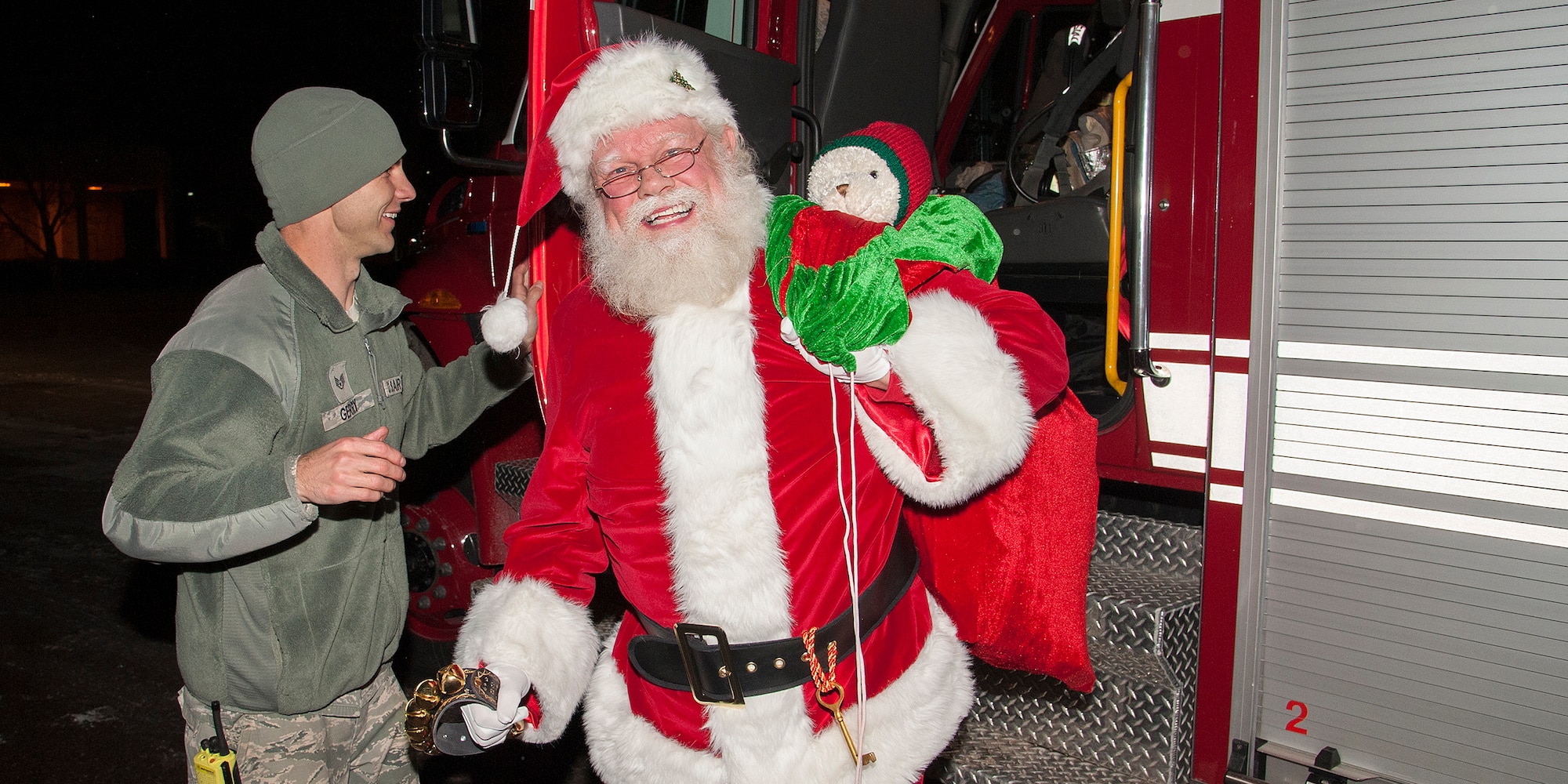 PETERSON AIR FORCE BASE, Colo. -- Staff Sgt. Robert Gerry Jr., 21st Space Wing Fire Department, assists Santa as he arrives at the Peterson Chapel. Santa took time out from his busy schedule to spend time with the good girls and boys at the base tree lighting ceremony Dec. 6. The event also featured photos with Santa, holiday music, refreshments, first responder display booths and a booth to make holiday cards to send to deployed troops. (U.S. Air Force photo/Craig Denton)
