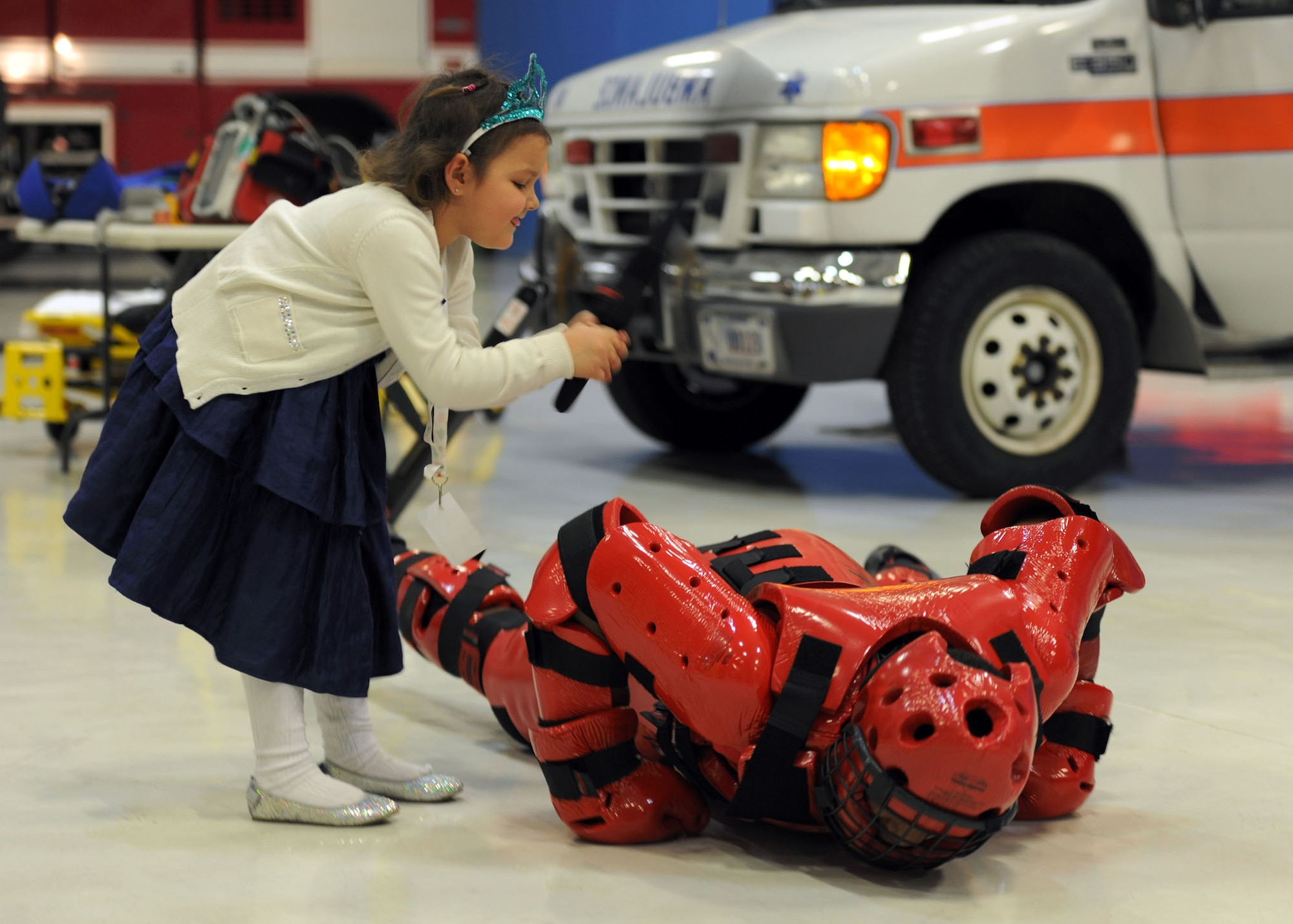 Emma Baker, 5, daughter of Capt. Mike Baker, Headquarters and Headquarters Company Commander, Walter Reed National Military Medical Center, demonstrates escalation of force tactics on Staff Sgt. James Watkins, 811th Security Force Squadron – Phoenix Ravens, Executive Aircraft Security Team member, at the 26th Annual Parents and Children Fighting Cancer Christmas Party Dec. 14, 2013 on Joint Base Andrews, Md. This allows PCFC families to spend the day in a winter wonderland offering food, entertainment, gifts, static displays, and a visit from Santa and Mrs. Claus. (U.S. Air Force photo/Aimee Fujikawa)