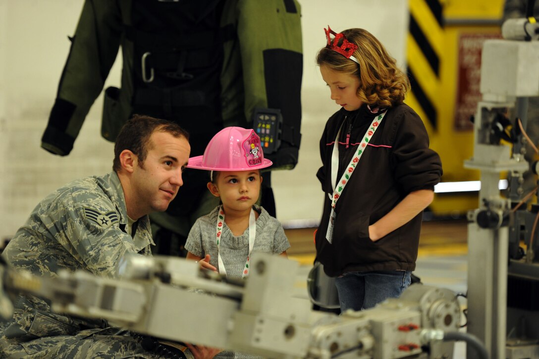 Senior Airman Brian Barry assists Audri, 2, and Ali, 7, daughters of CTM1 Leslie Trotta, stationed at Joint Base Anacostia-Boling, Md. operate the F6 EOD robot at the 26th Annual Parents and Children Fighting Cancer Christmas Party on Dec. 14, 2013 in Hangar 3 on Joint Base Andrews, Md. This event allowed PCFC families to spend the day in a winter wonderland offering food, entertainment, gifts, static displays, and a visit from Santa and Mrs. Claus. Barry is an 11th Wing Civil Engineer Squadron Explosive Ordinance Disposal technician. (U.S. Air Force photo/Aimee Fujikawa)