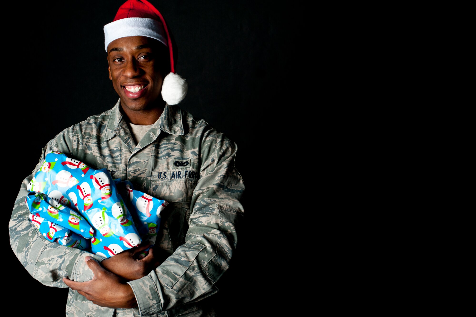 Senior Airman DeLorean Gulledge, 91st Security Support Squadron keys and code control center member poses with gifts while wearing a Santa hat at Minot Air Force Base, Dec. 11, 2013. KCCC and missile security control Airmen have rigorous schedules that prevent them from enjoying the holidays in the same way as so many others do, they are not the only units who make sacrifices during the holidays. During the weeks ahead, while Airmen and their families are celebrating together, there will be so many others dedicating their holiday season to the mission. (U.S. Air Force photo/Senior Airman Brittany Y. Auld)
