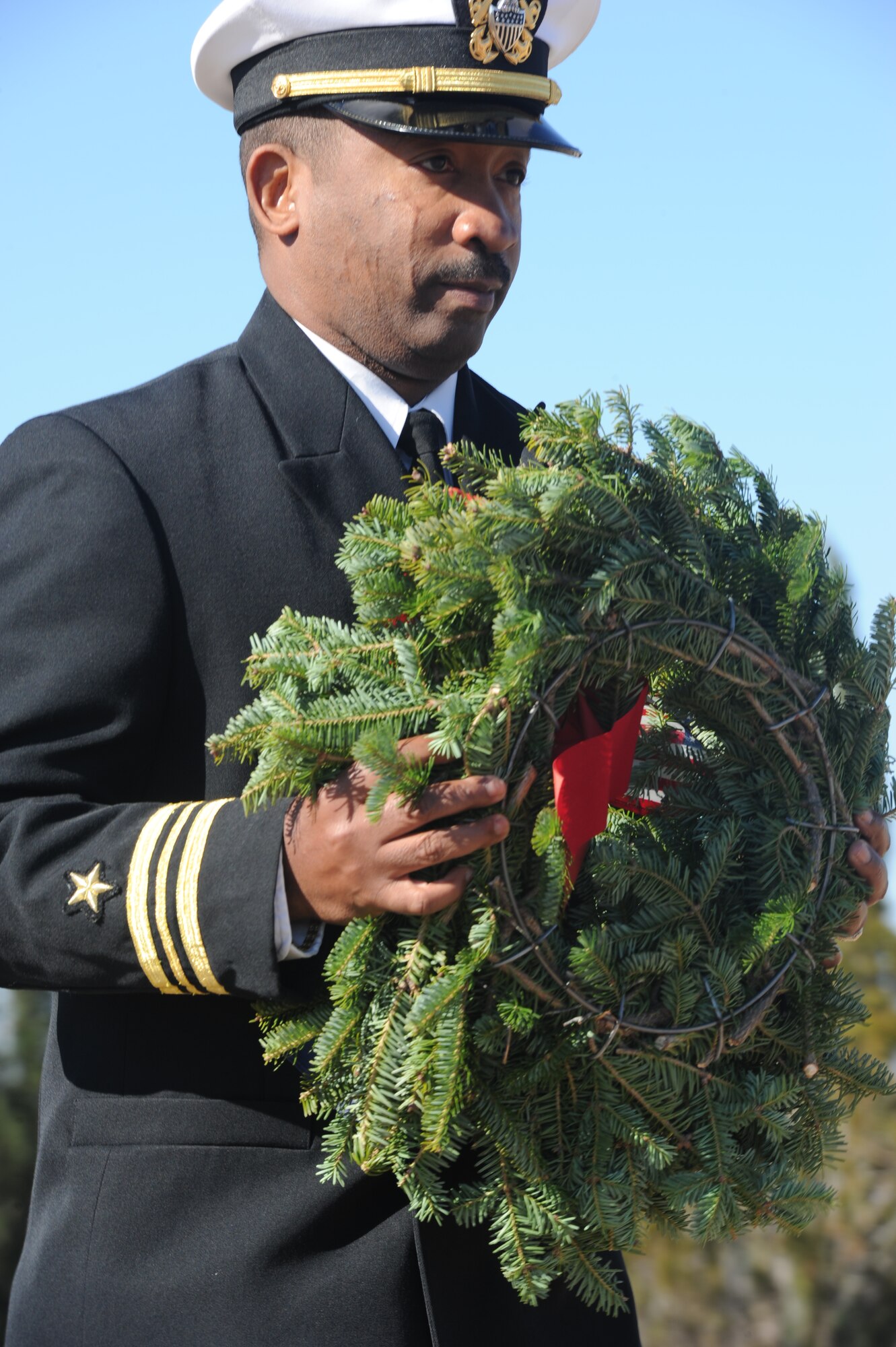 SAN ANGELO, Texas – Navy Lt. Cmdr. Cornell Woods, Navy Center for Information Dominance Detachment Commanding Officer, carries a wreath to the base of the flagpole at the Belvedere Cemetery during the Wreaths Across America ceremony Dec. 14. The mission of Wreaths Across America is Remember, Honor, Teach; Remember the Fallen, honor those who serve and teach our children the value of freedom. (U.S. Air Force photo/ Staff Sgt. Laura R. McFarlane)