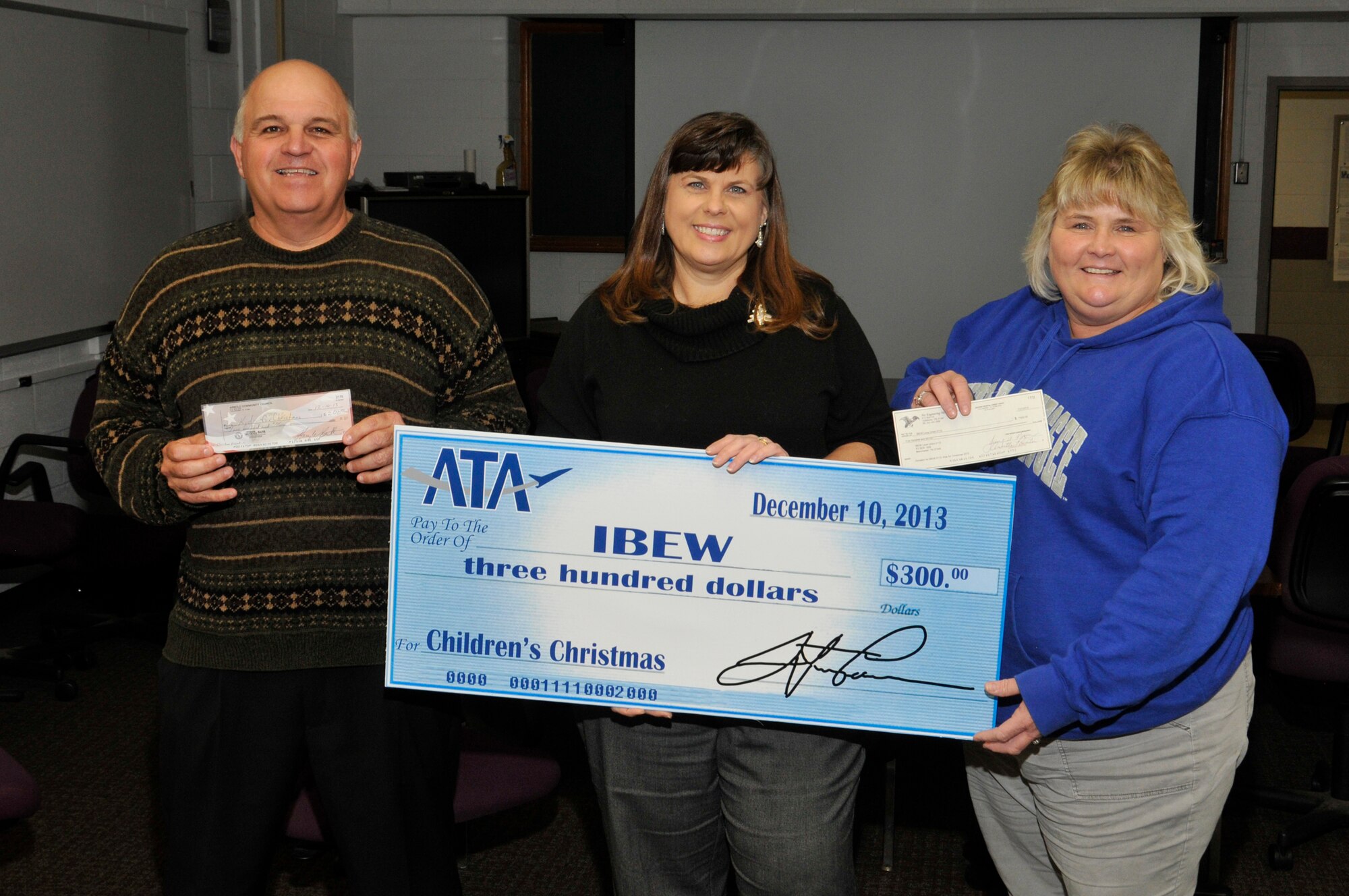 Air Engineering Metal Trades Council (AEMTC) President Jimmy Nance (left), Carol Smith (center), an admin for the AEDC Fire Department, and Annette Painter, a financial secretary for the International Brotherhood of Electrical Workers 2113, hold checks for the Kids for Christmas event held on Saturday, Dec. 14. The AEMTC, ATA and the Arnold Community Council (a support group for AEDC) all made donations.  The money raised helped foster children buy presents for their loved ones. (Photo by Rick Goodfriend)