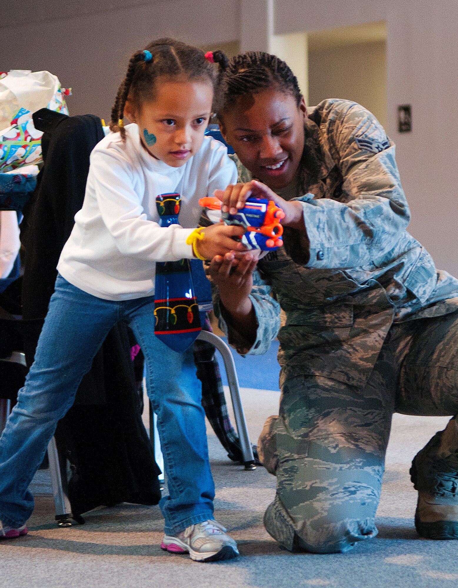Airman 1st Class Jasmine Braxton, 90th Security Forces Squadron, helps Rachel Johnson, 5, aim a toy gun Santa gave her at Operation Provide Joy in the Fall Hall Community Center, Dec. 14, 2013. Donated toys were given to children from local families invited to F.E. Warren Air Force Base, Wyo., to celebrate Christmas with Airmen and Santa Claus. (U.S. Air Force photo by R.J. Oriez)