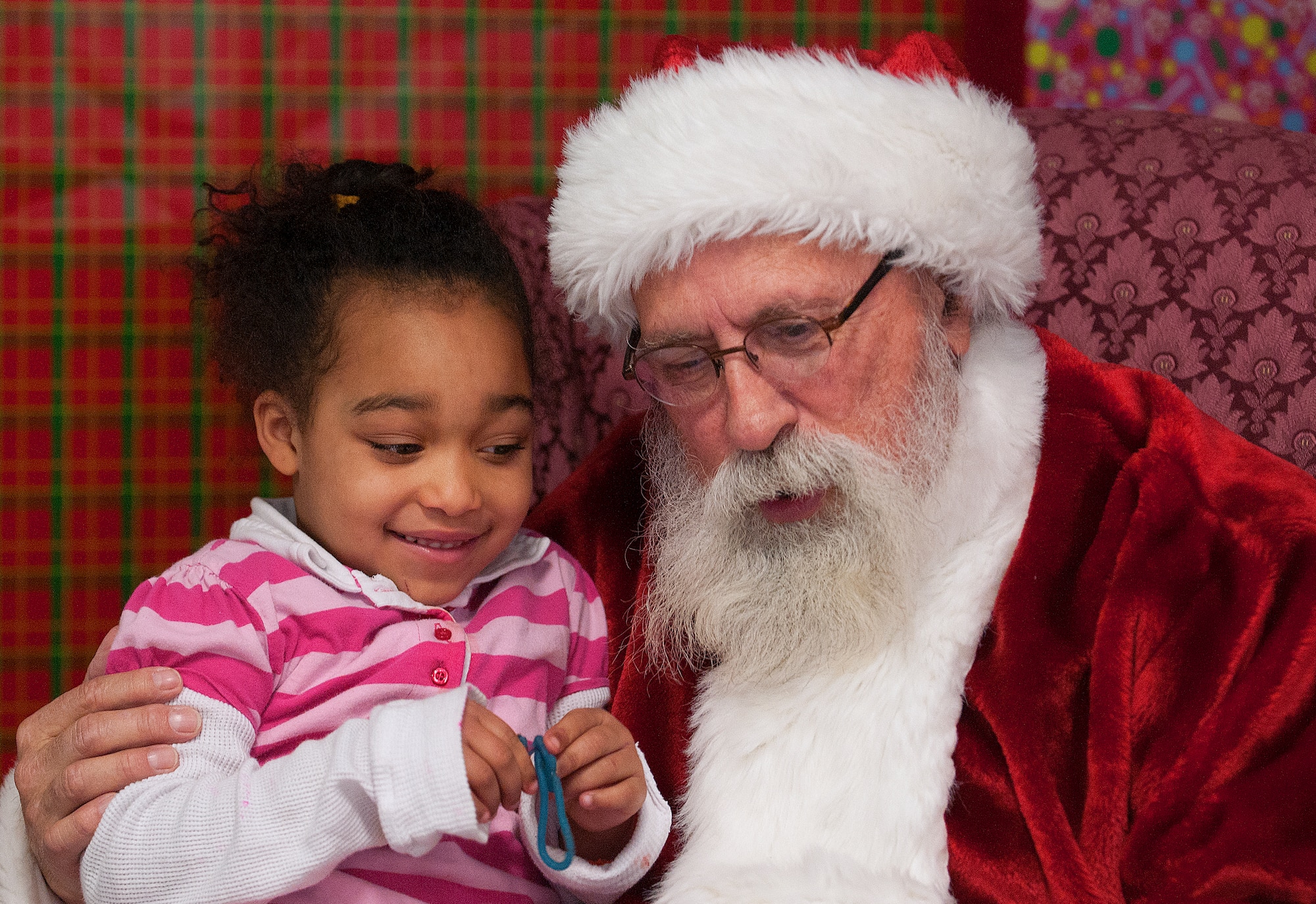 Santa leans in to hear what Zyanna Brown, 5, wants for Christmas. Zyanna got the chance to visit with Santa during the annual Operation Provide Joy in the Fall Hall Community Center Dec. 14, 2013. (U.S. Air Force photo by R.J. Oriez)