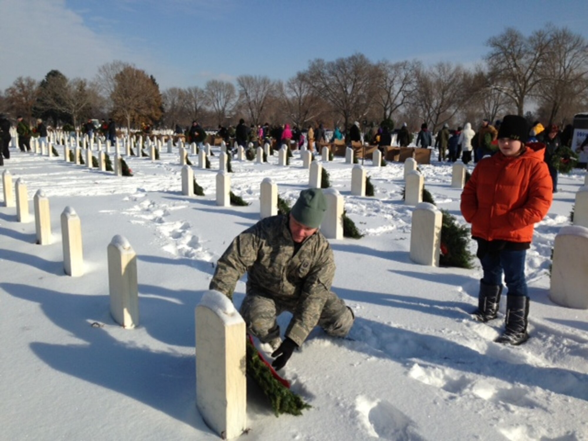 Master Sgt. Conrad Kluck, 934th Maintenance Squadron, places a wreath on a grave at Fort Snelling National Cemetery, Minn. as his daughter Ella(11) looks on. Wreaths were placed as part of the Wreaths Across America event Dec. 14. (Air Force Photo/Maj. Sabra Brown)