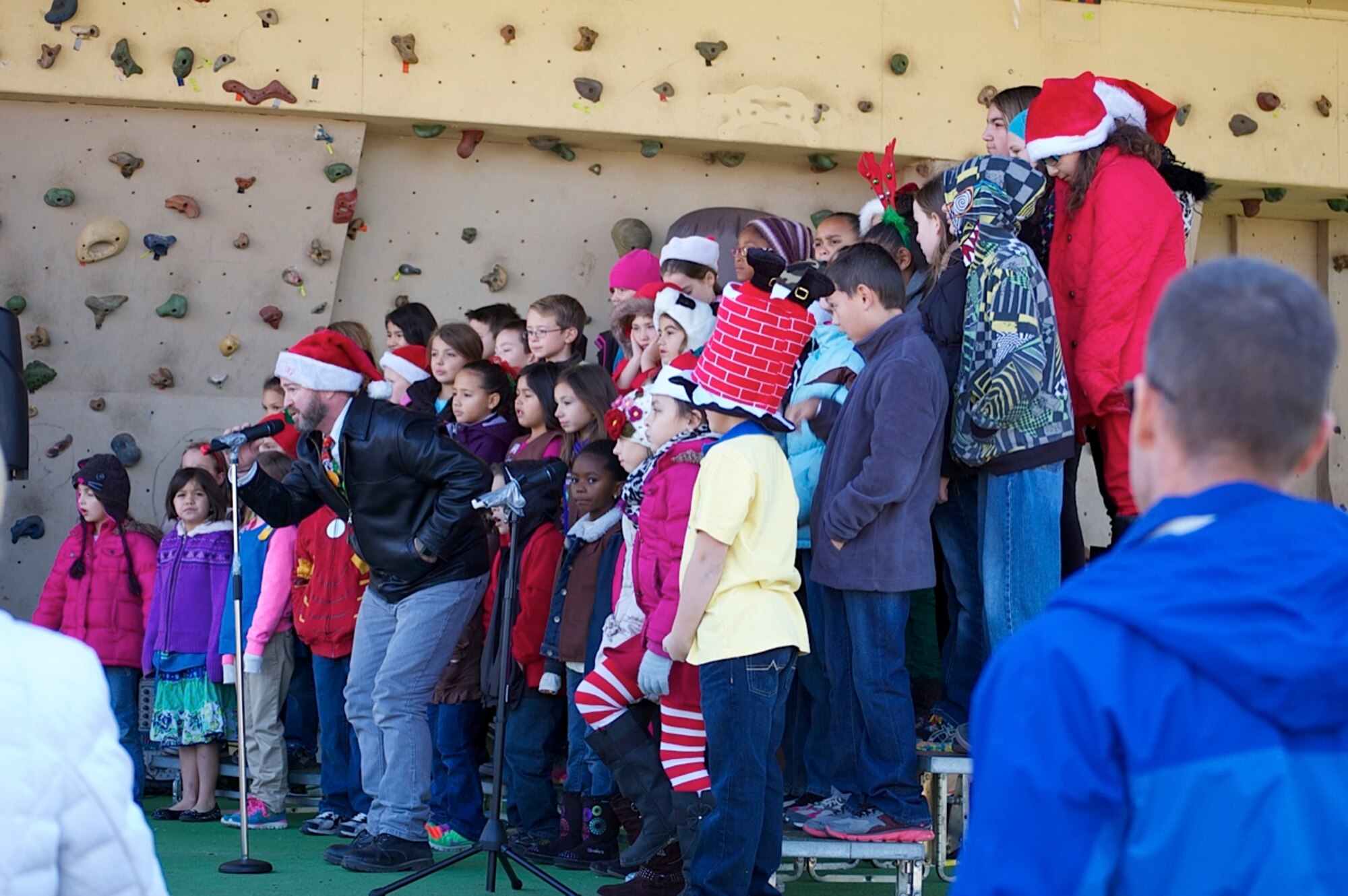 Shannon Daniels, Incirlik Unit School K – 5 choir director, leads the IUS choir as they sing a holiday carol to attendees of Winter Fest Dec. 14, 2013, at Incirlik Air Base, Turkey. Incirlik AB’s first Winter Fest welcomed the season with cups of warm chocolate, a fire pit of burning logs and Santa Paws to take pictures with Team Incirlik’s furry family members. (Courtesy photo by Kristina Liapis)
