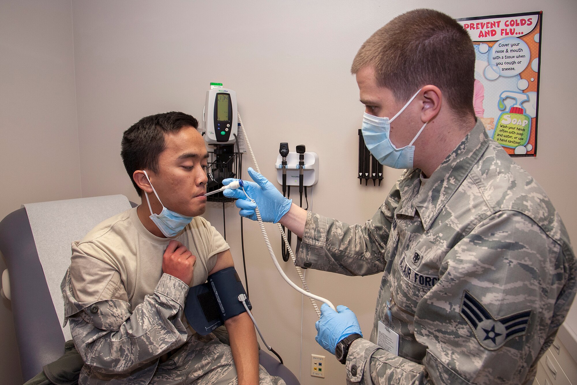 PETERSON AIR FORCE BASE, Colo. -- Senior Airman Thomas Carlson (right), 21st Medical Operations Squadron, checks the blood pressure and temperature of 2nd Lt. Edward Garces, 21st Aerospace Medicine Squadron, after Garces complained of flu like symptoms. The medical check-up was part of an exercise scenario Dec. 4 where influenza developed in the Pacific and swept through the country onto Peterson. The 21st MDG set up vaccine distribution points at Peterson, Schriever Air Force Base and Cheyenne Mountain Air Force Station, and countered the threat by prioritizing the administration of limited preventive medicine. (U.S. Air Force photo/Craig Denton)