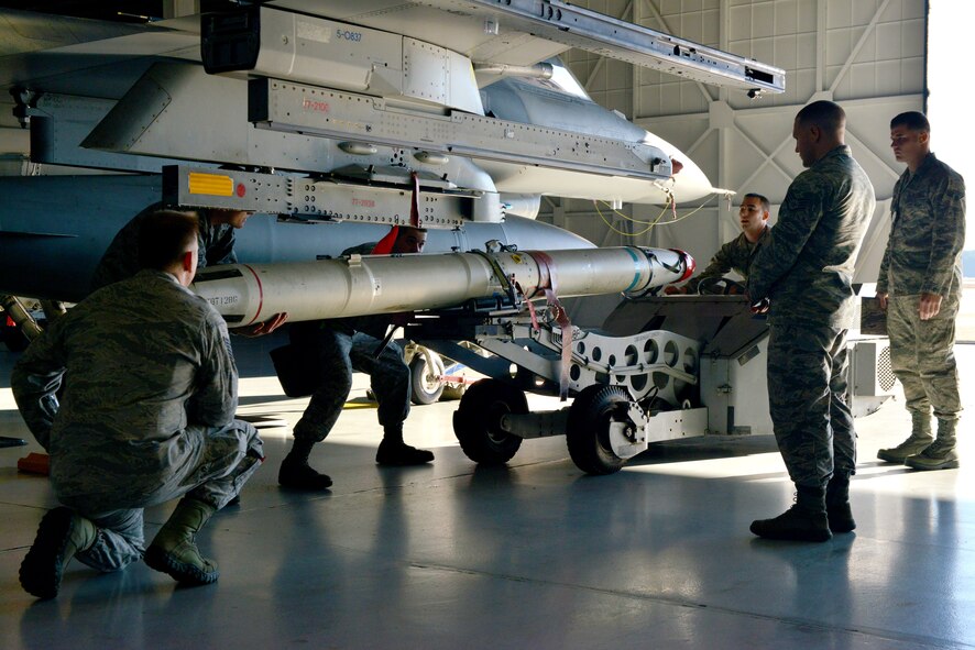 U.S. Air Force Airmen from the 20th Aircraft Maintenance Squadron, Shooter Aircraft Maintenance Unit weapons load crew team prepare to attach a missile on an F-16 Fighting Falcon, Shaw Air Force Base, S.C., Dec. 13, 2013. The crew was being evaluated throughout the process to ensure they were following proper loading procedure. (U.S. Air Force photo by Airman 1st Class Jensen Stidham/Released)